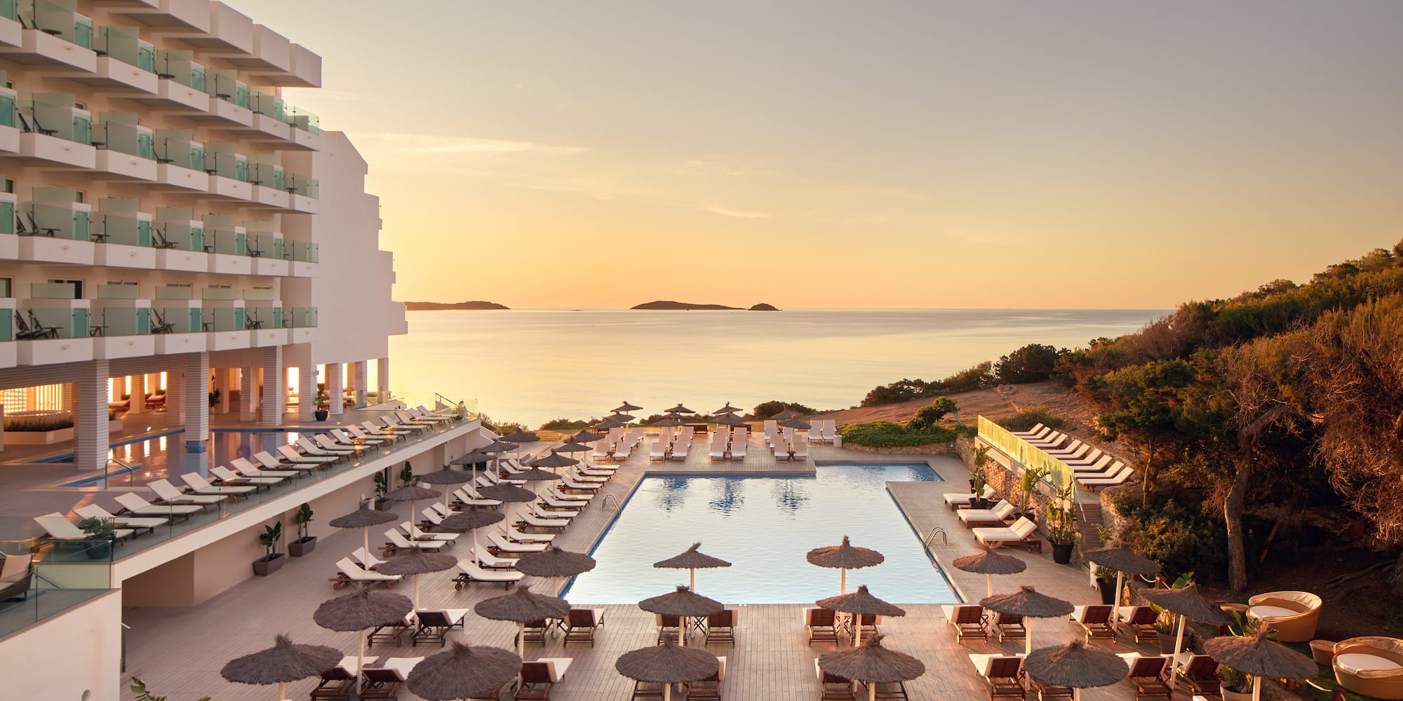a pool with umbrellas and chairs and a building with a body of water