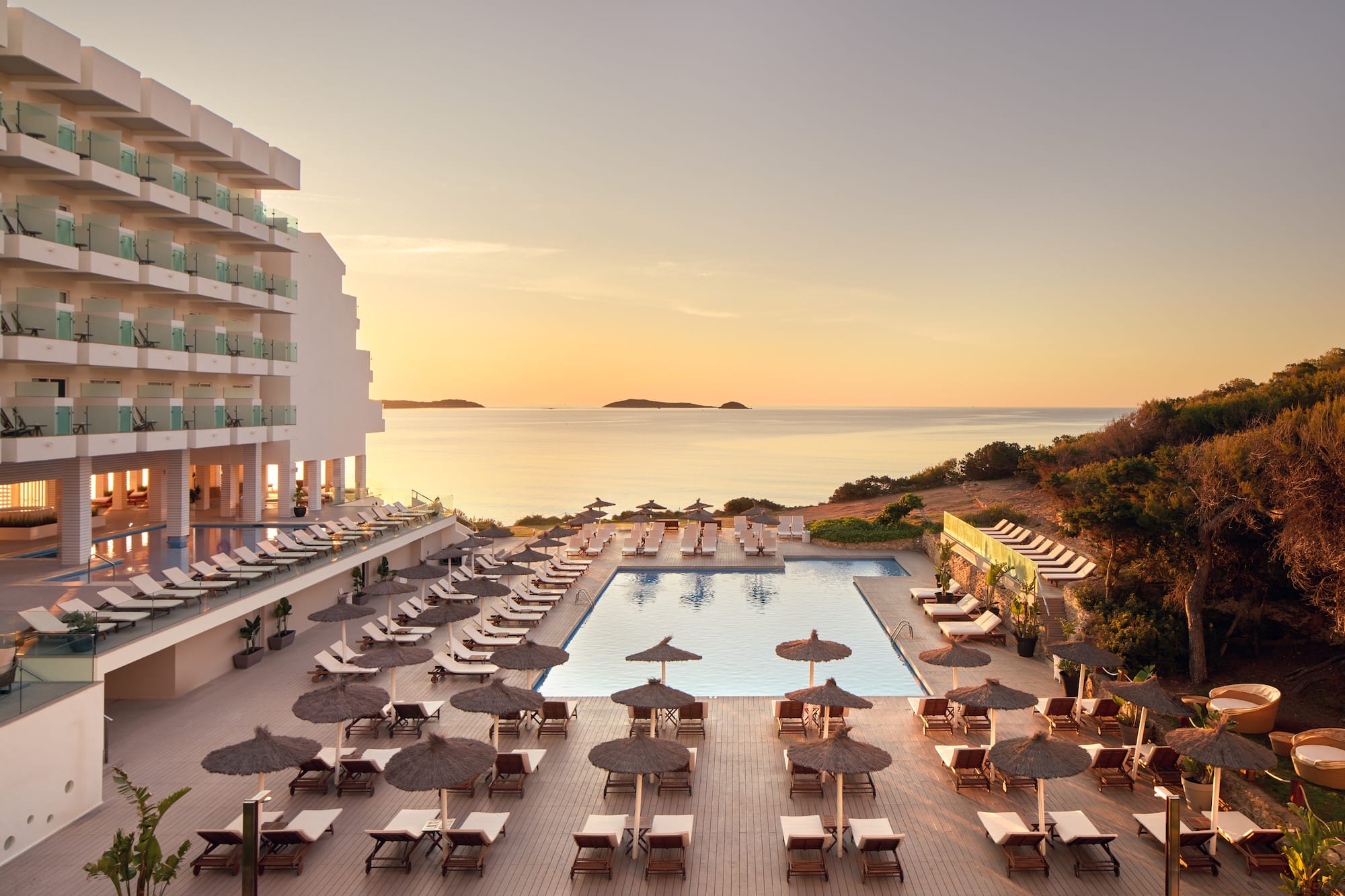 a pool with umbrellas and chairs and a building with a body of water