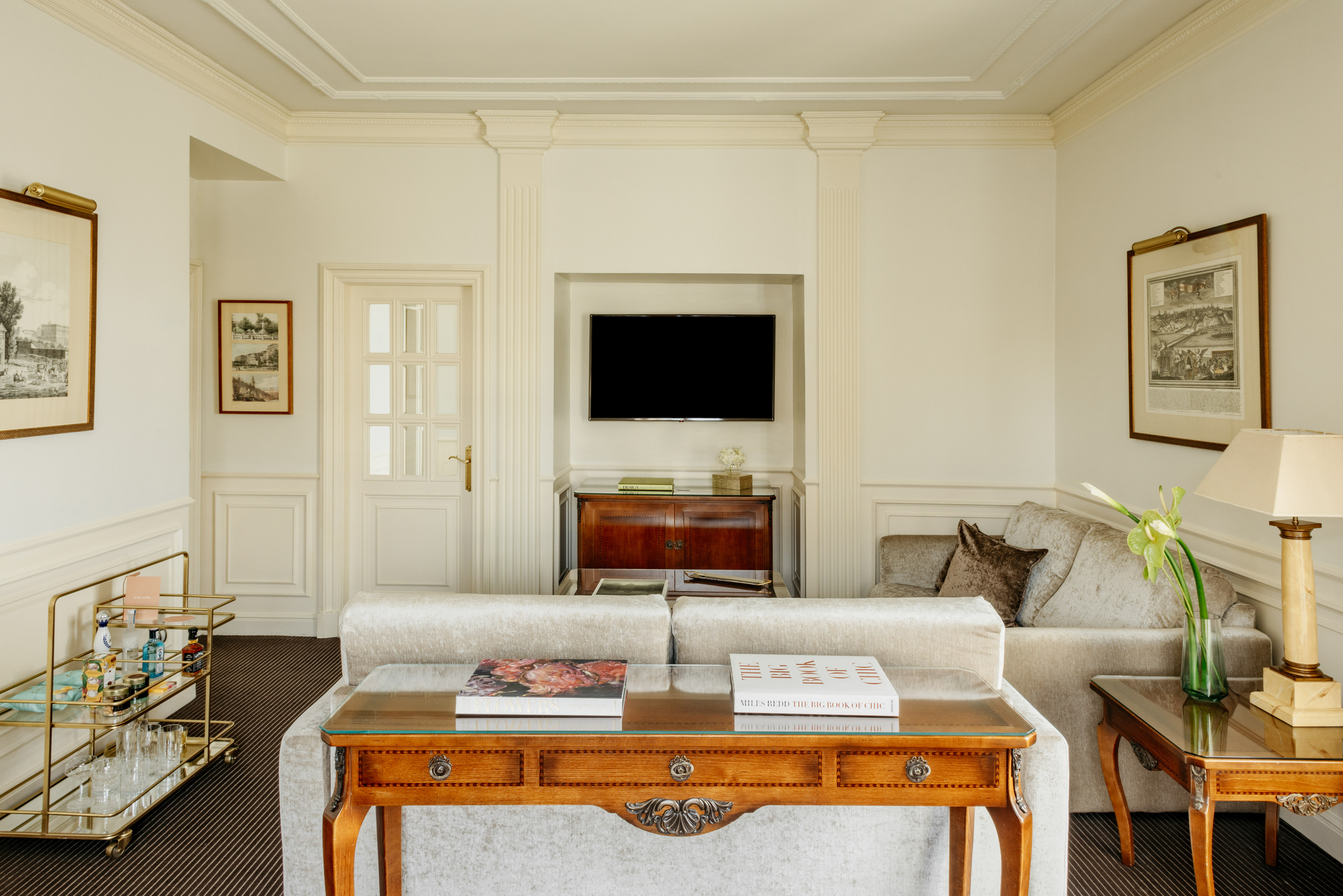 Luxury hotel living room with velvet sofas, classic furniture, and TV.