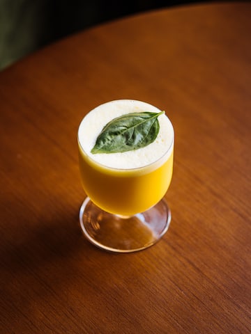 a glass with a yellow drink and a leaf on top