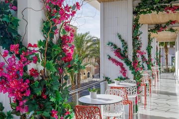 a white tables and chairs with pink flowers on a white wall