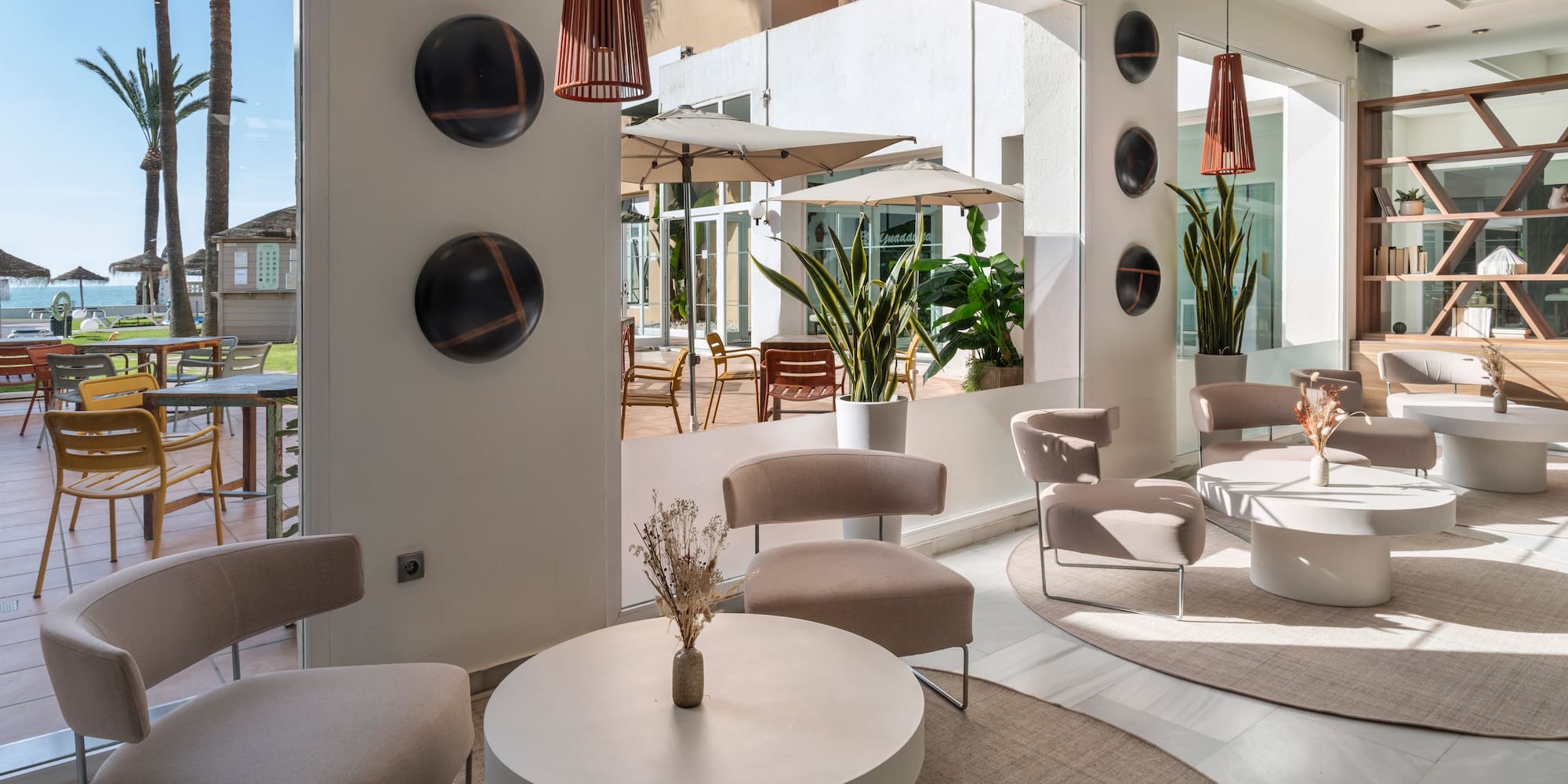Modern hotel lounge with stylish seating, outdoor patio, and sea view.