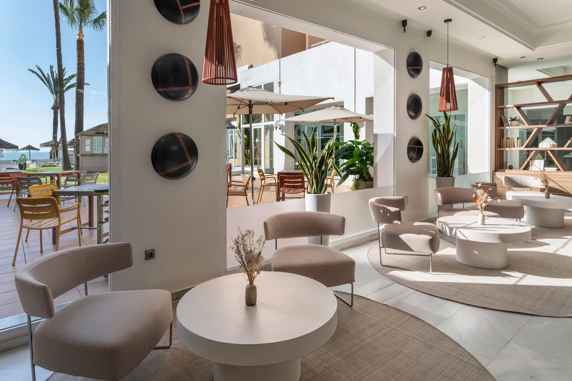 Modern hotel lounge with stylish seating, outdoor patio, and sea view.