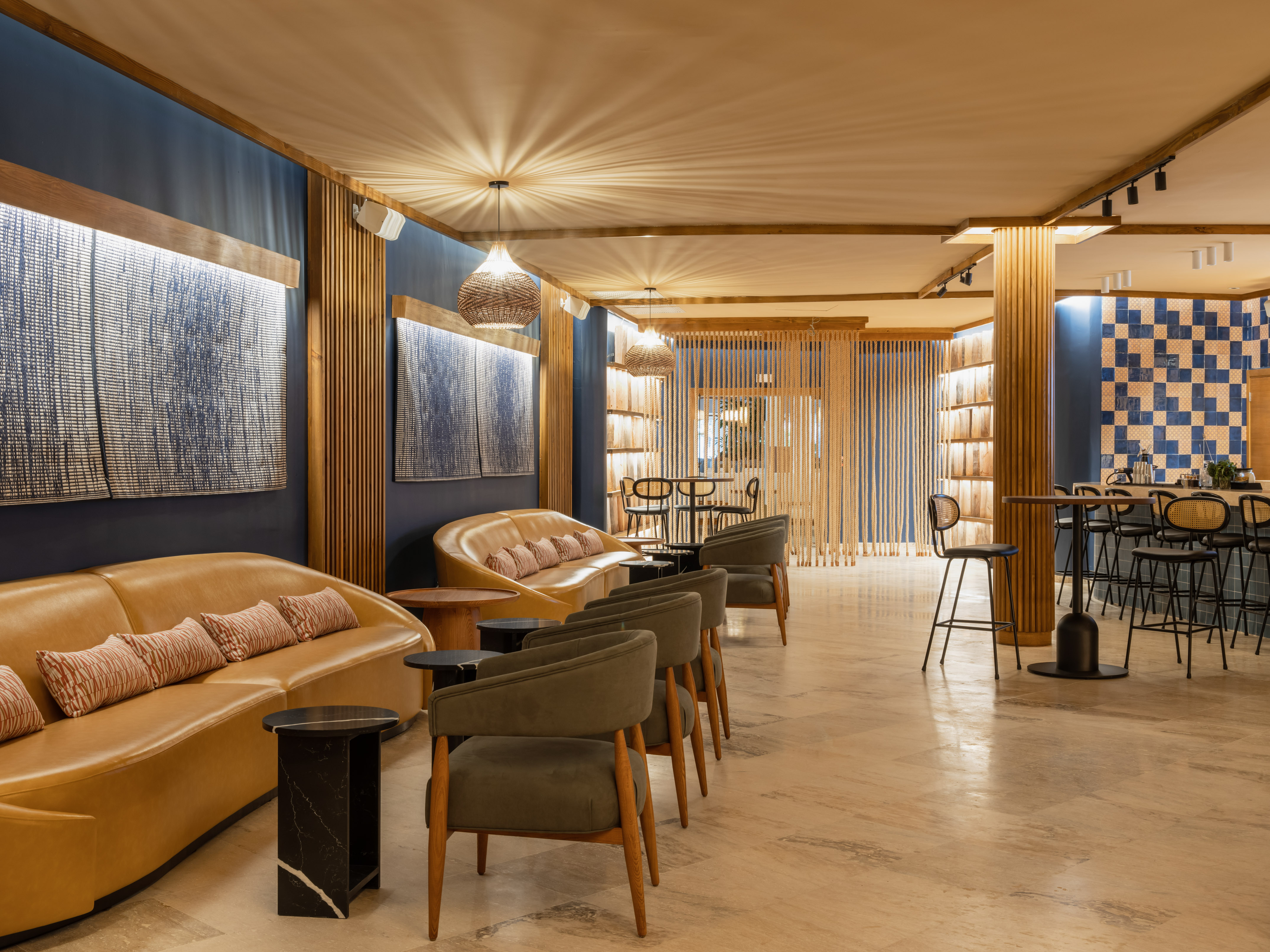 Modern lounge bar interior with tan sofas, olive chairs, blue walls.