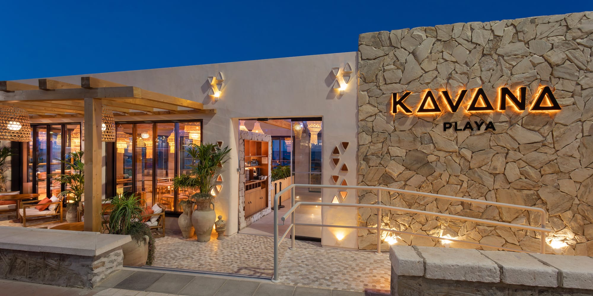 Kavana Playa restaurant exterior at dusk with backlit sign and modern patio.