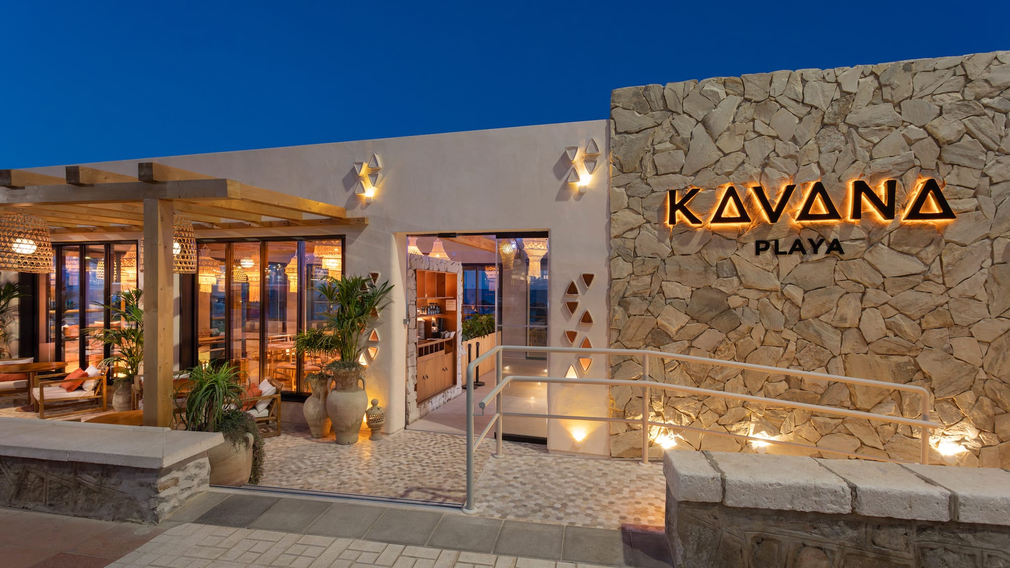 Kavana Playa restaurant exterior at dusk with backlit sign and modern patio.