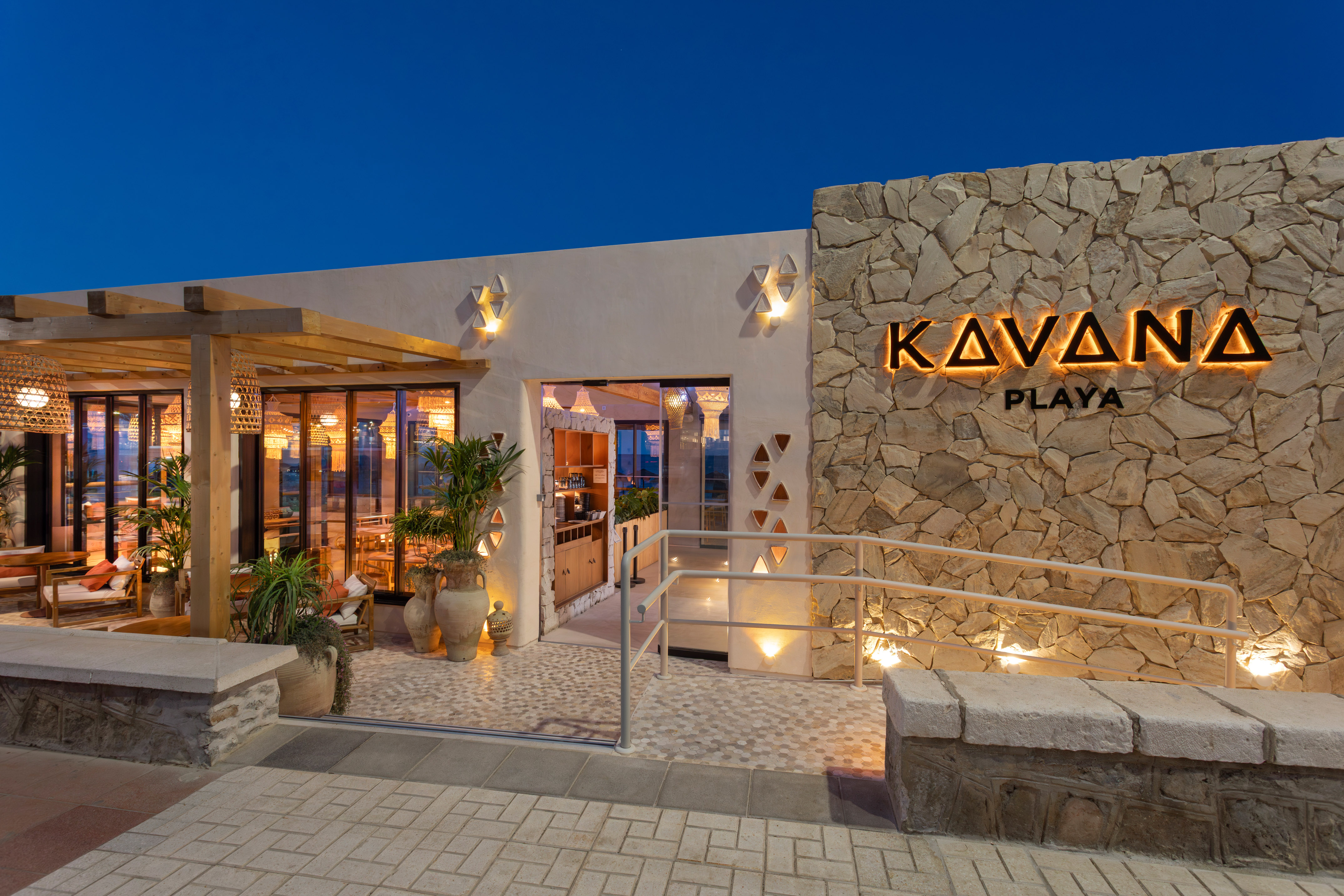 Kavana Playa restaurant exterior at dusk with backlit sign and modern patio.