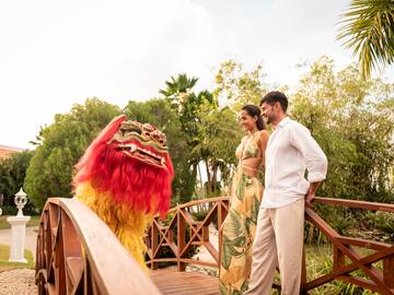 a man and woman standing on a bridge with a lion garment