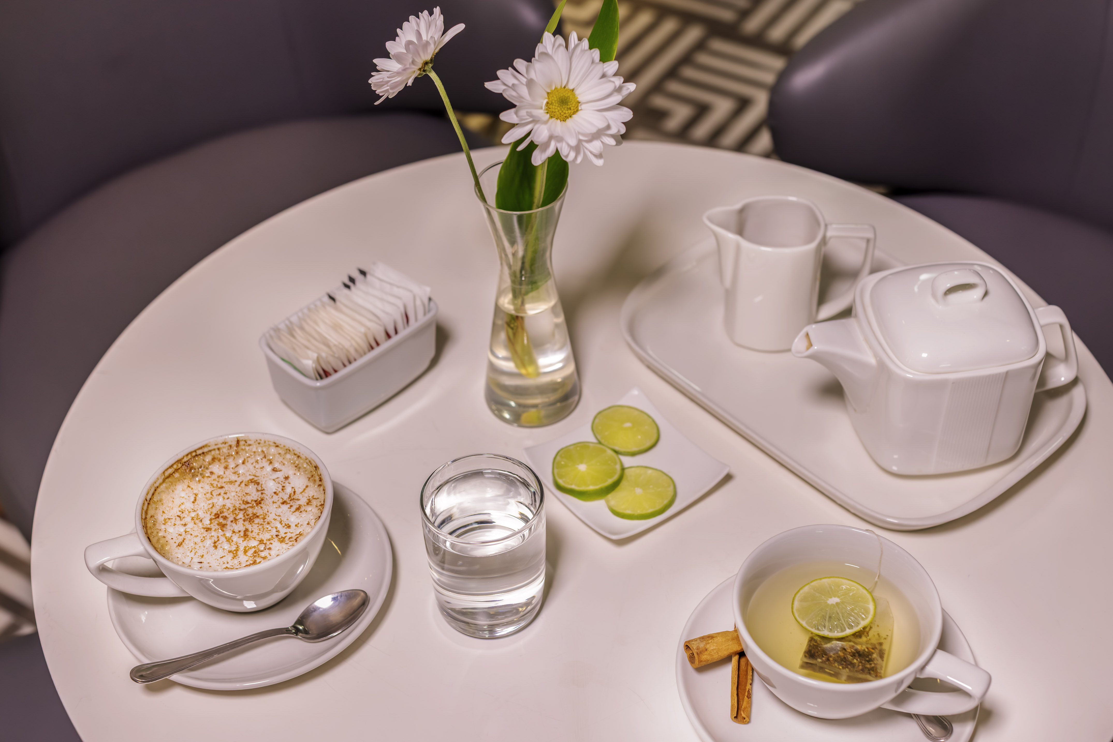 a table with a cup of tea and a vase of flowers