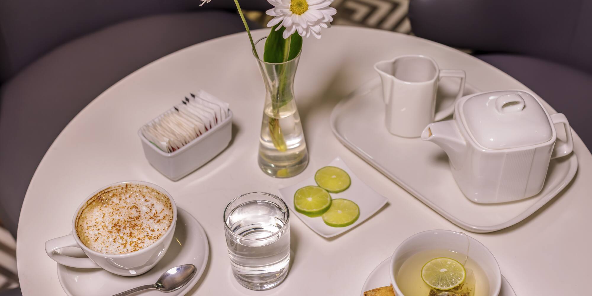 a table with a cup of tea and a vase of flowers