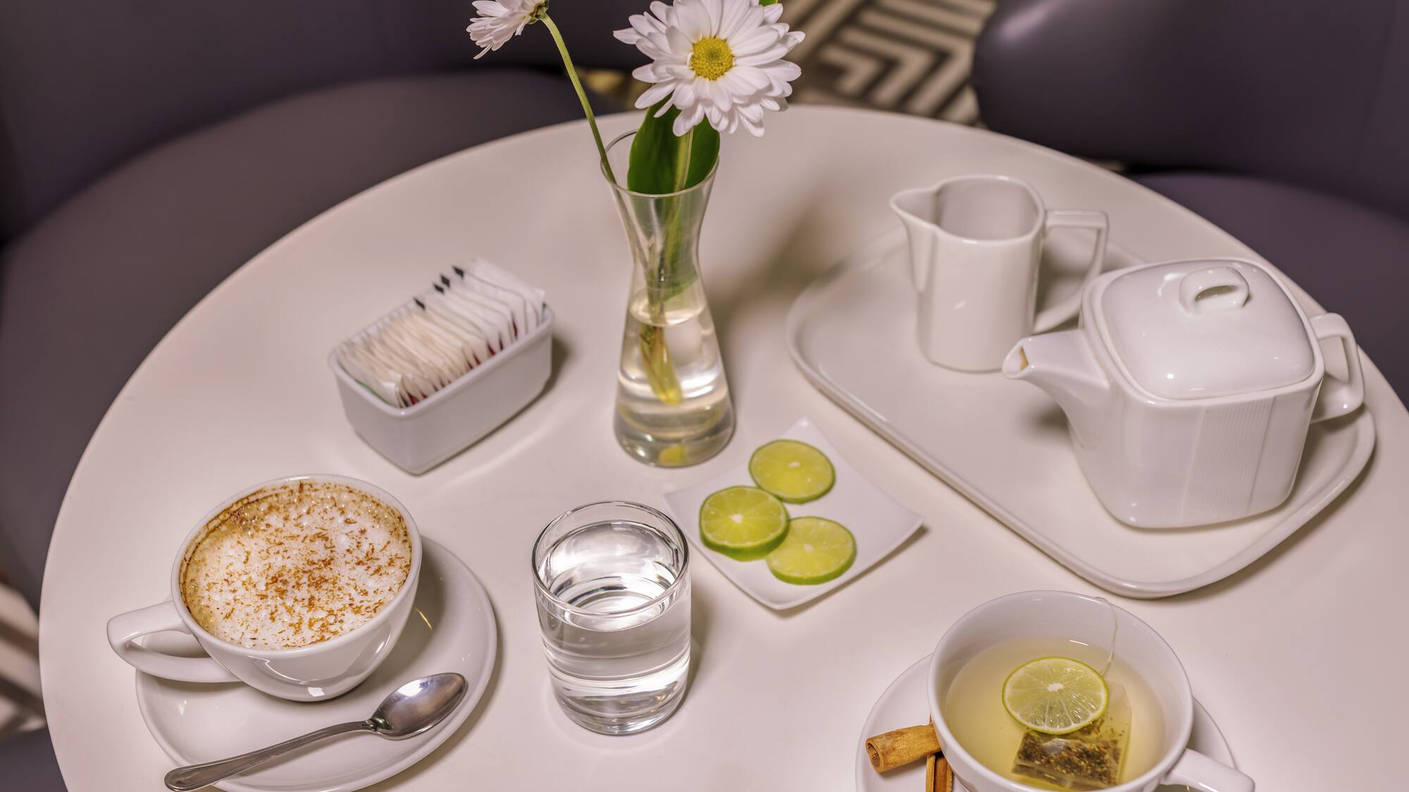a table with a cup of tea and a vase of flowers