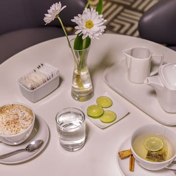 a table with a cup of tea and a vase of flowers