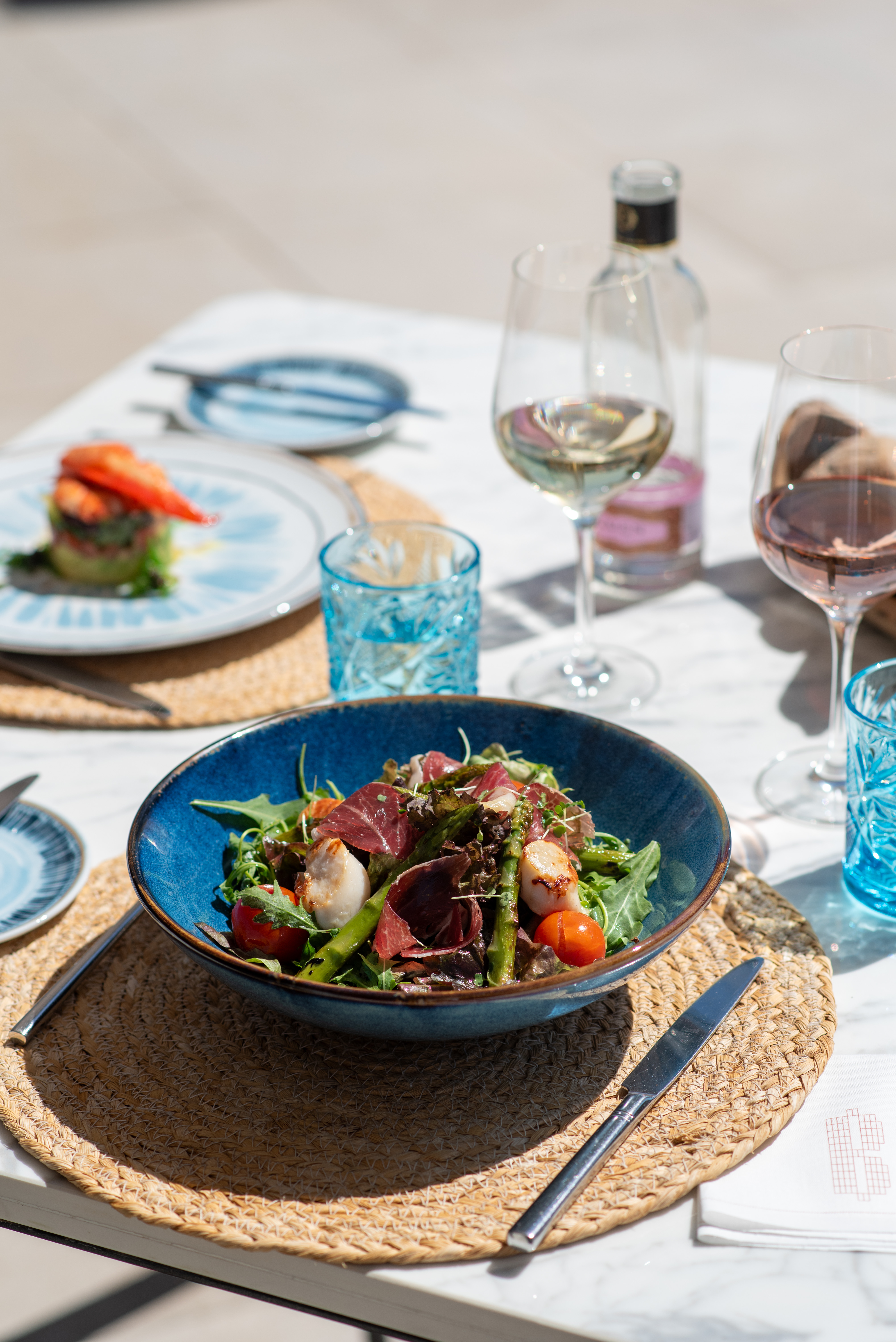 Scallop, prosciutto, asparagus salad with tomatoes, outdoor dining with wine.