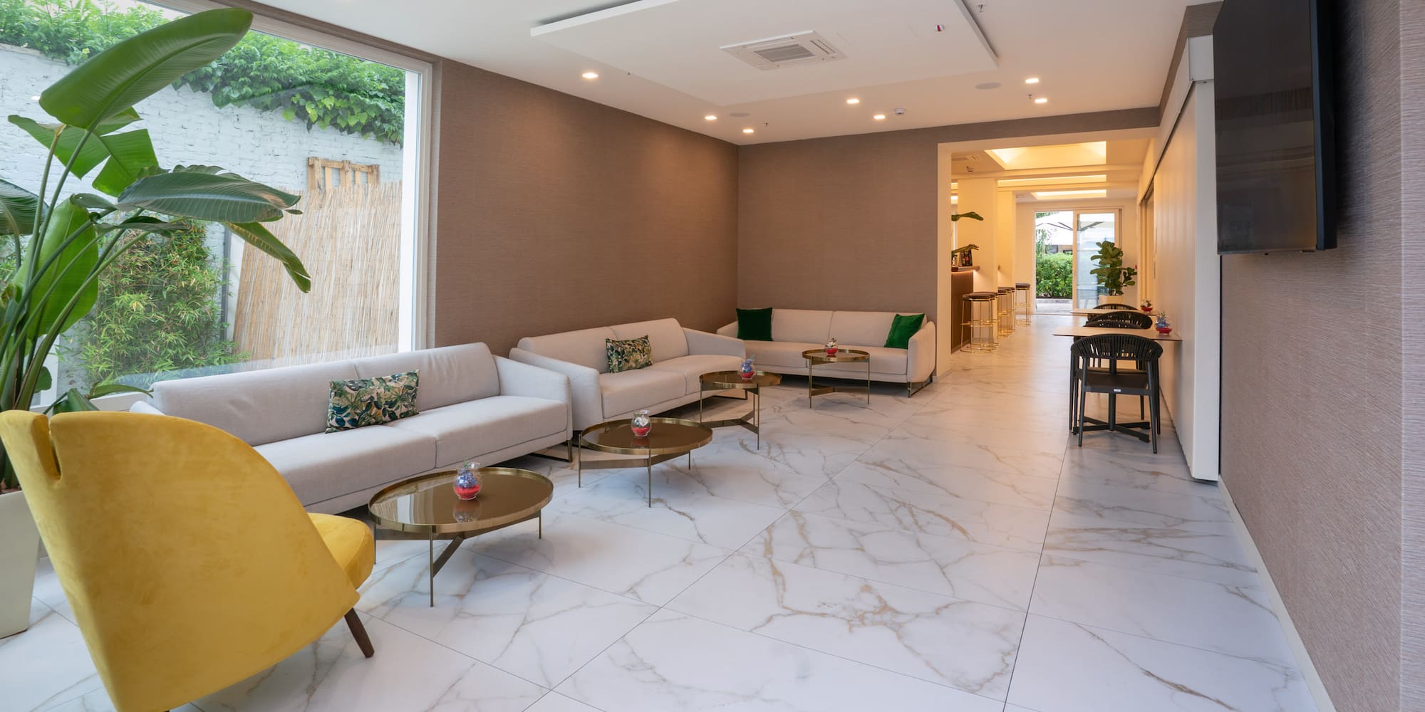 Modern hotel lobby with cream sofas, gold tables, and white marble flooring.