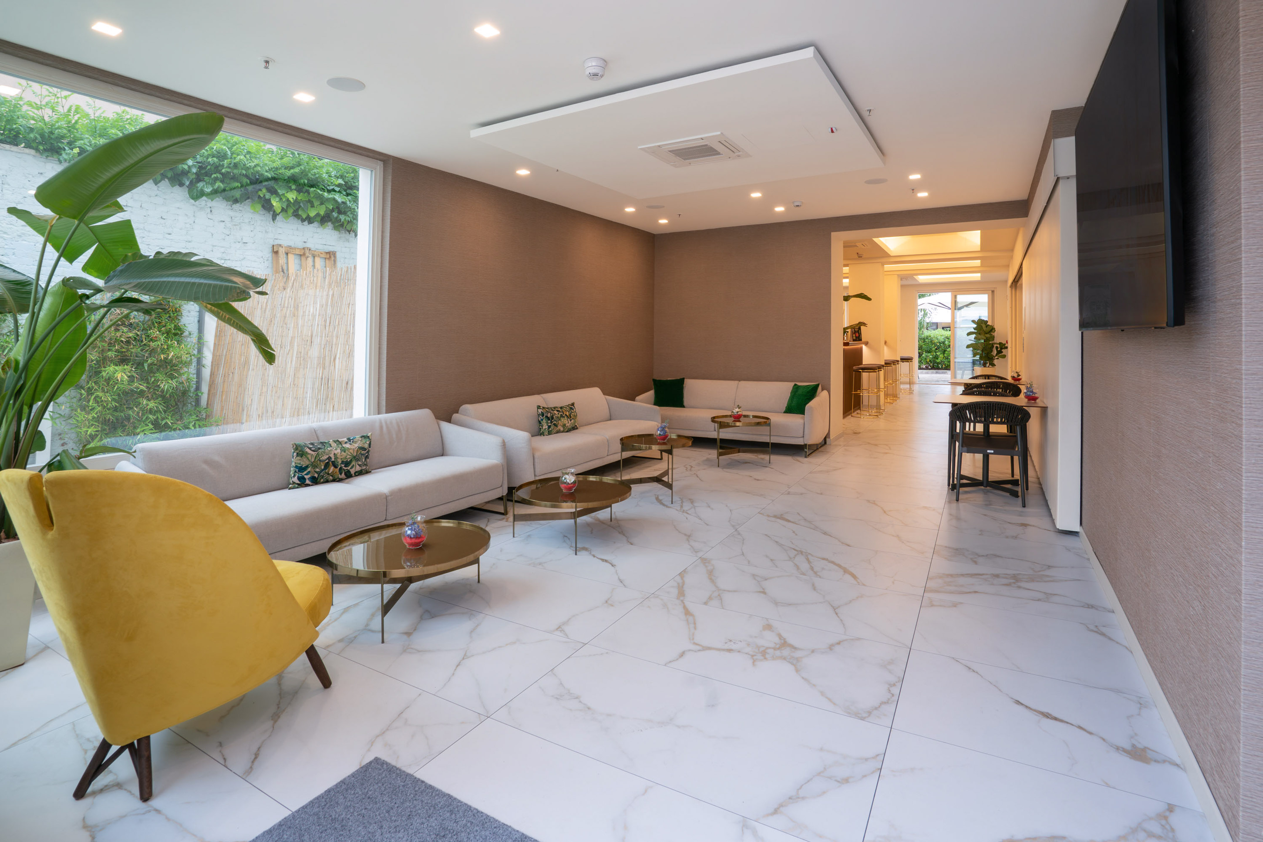 Modern hotel lobby with cream sofas, gold tables, and white marble flooring.