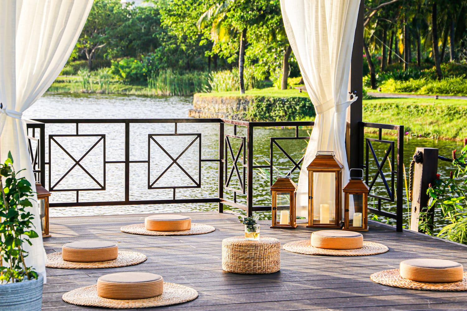 a deck with a white curtain and a white curtain and a round table with round objects on it