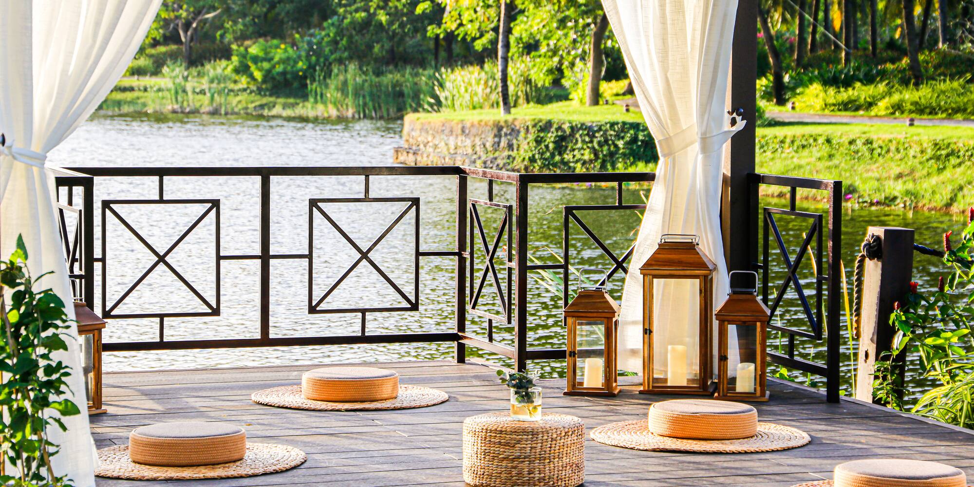 a deck with a white curtain and a white curtain and a round table with round objects on it