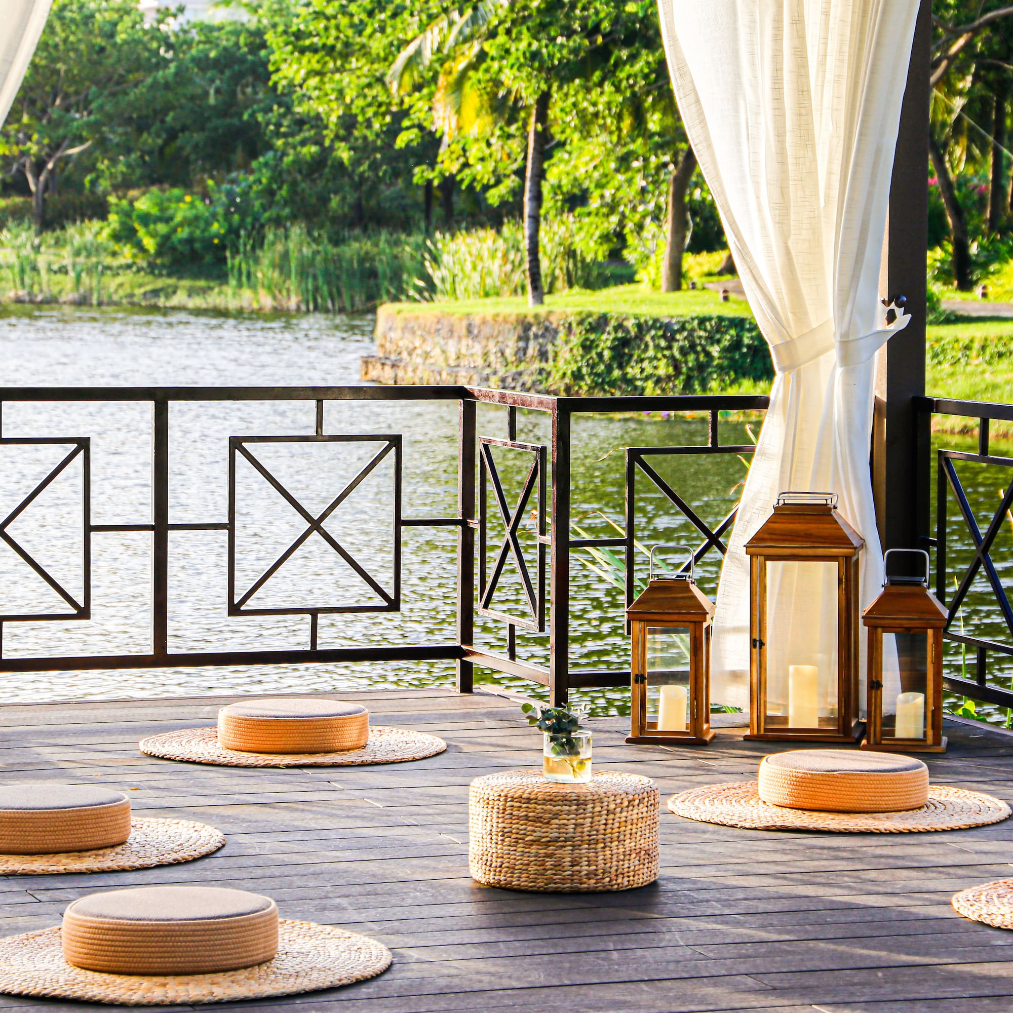 a deck with a white curtain and a white curtain and a round table with round objects on it