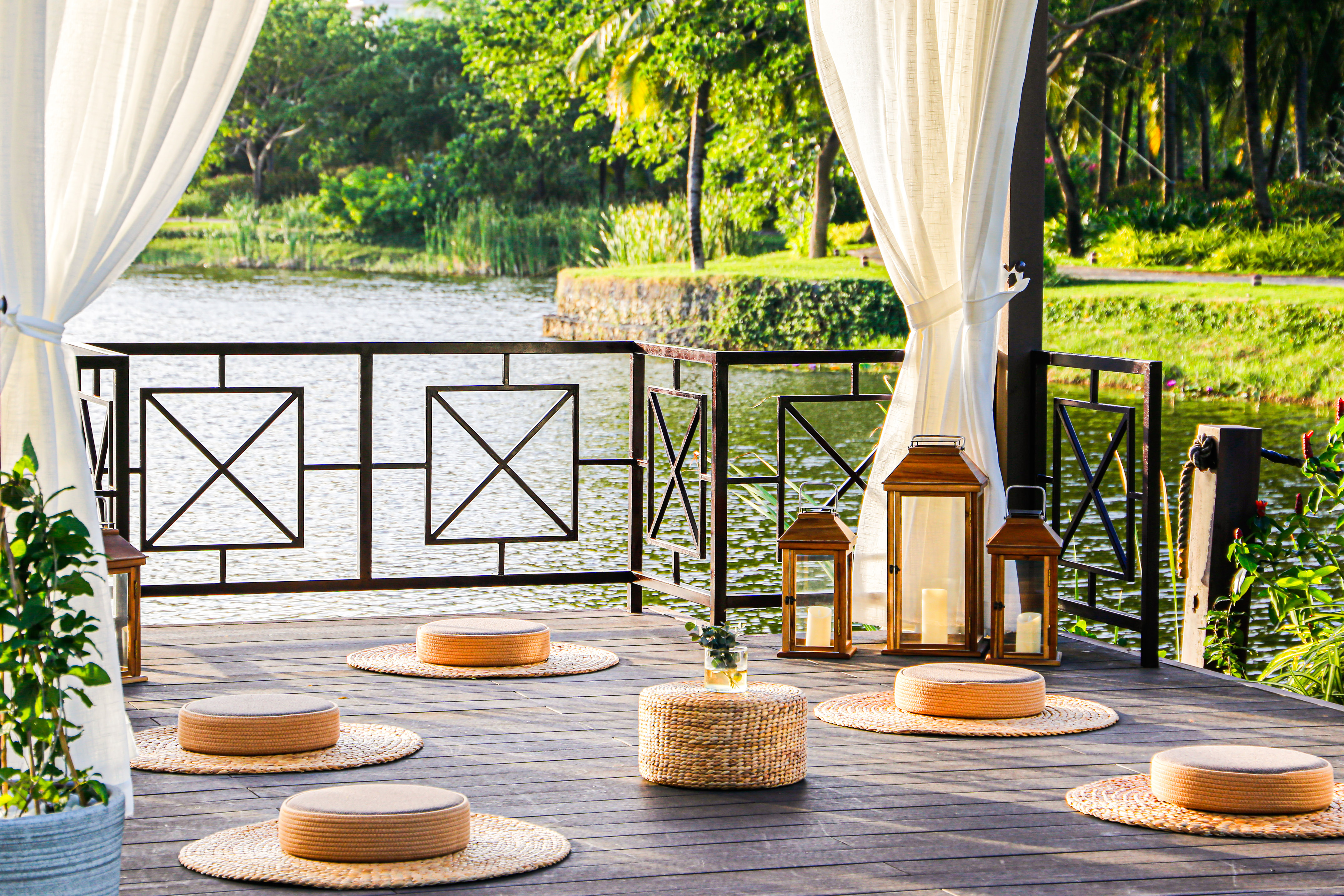 a deck with a white curtain and a white curtain and a round table with round objects on it