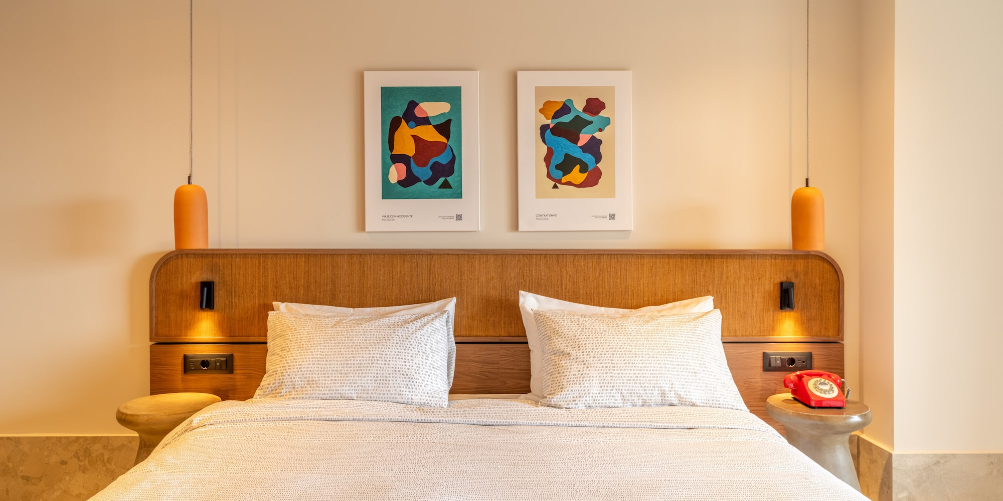 a bed with pillows and a table with two lamps above it