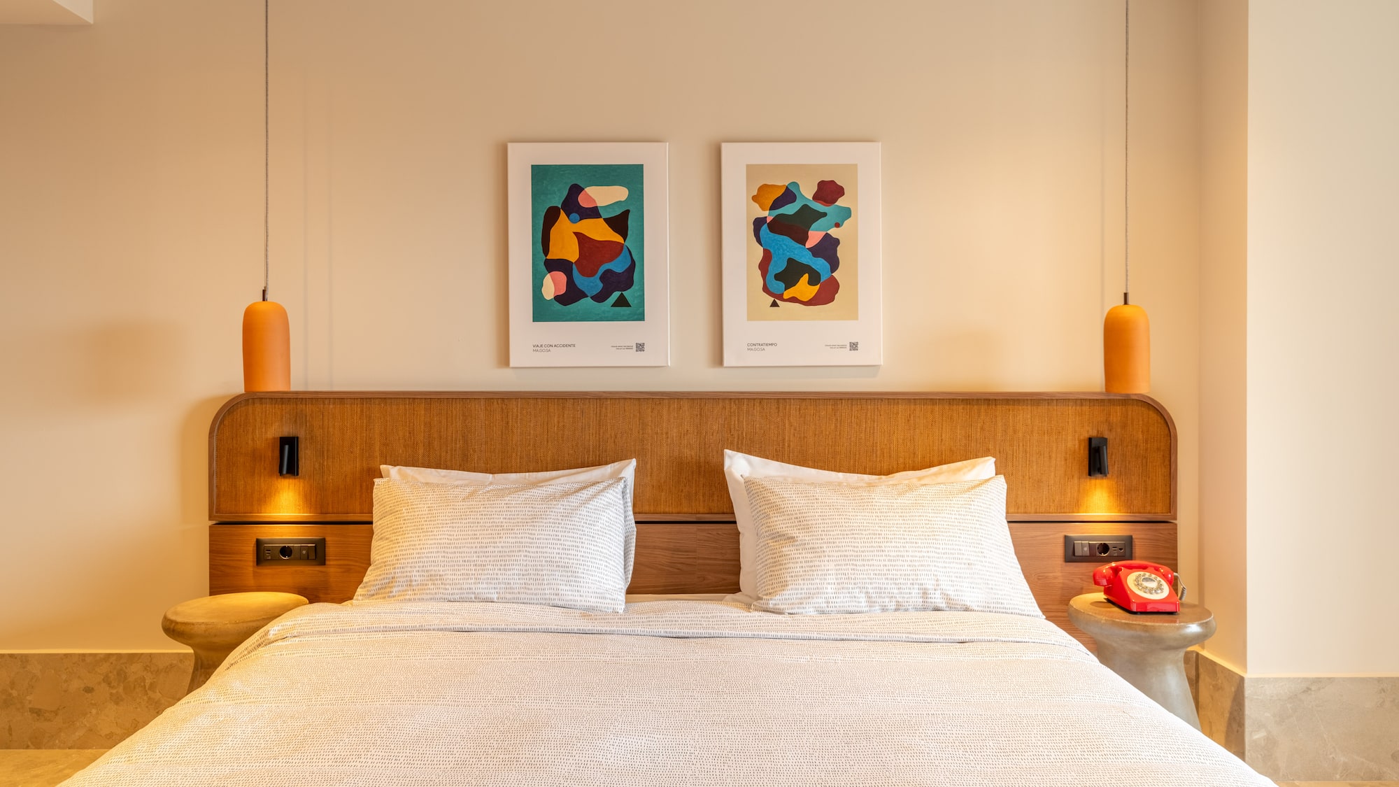 a bed with pillows and a table with two lamps above it