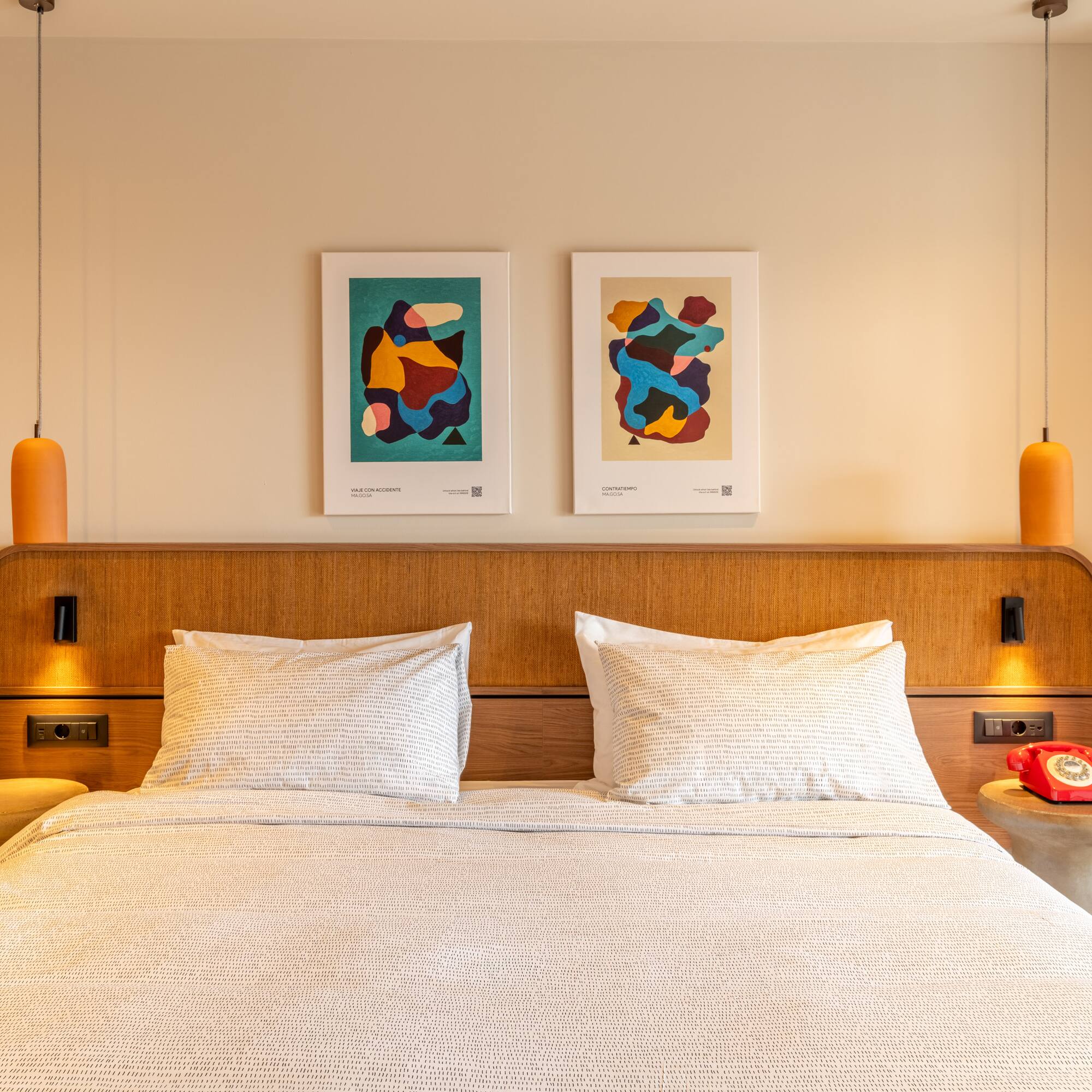 a bed with pillows and a table with two lamps above it