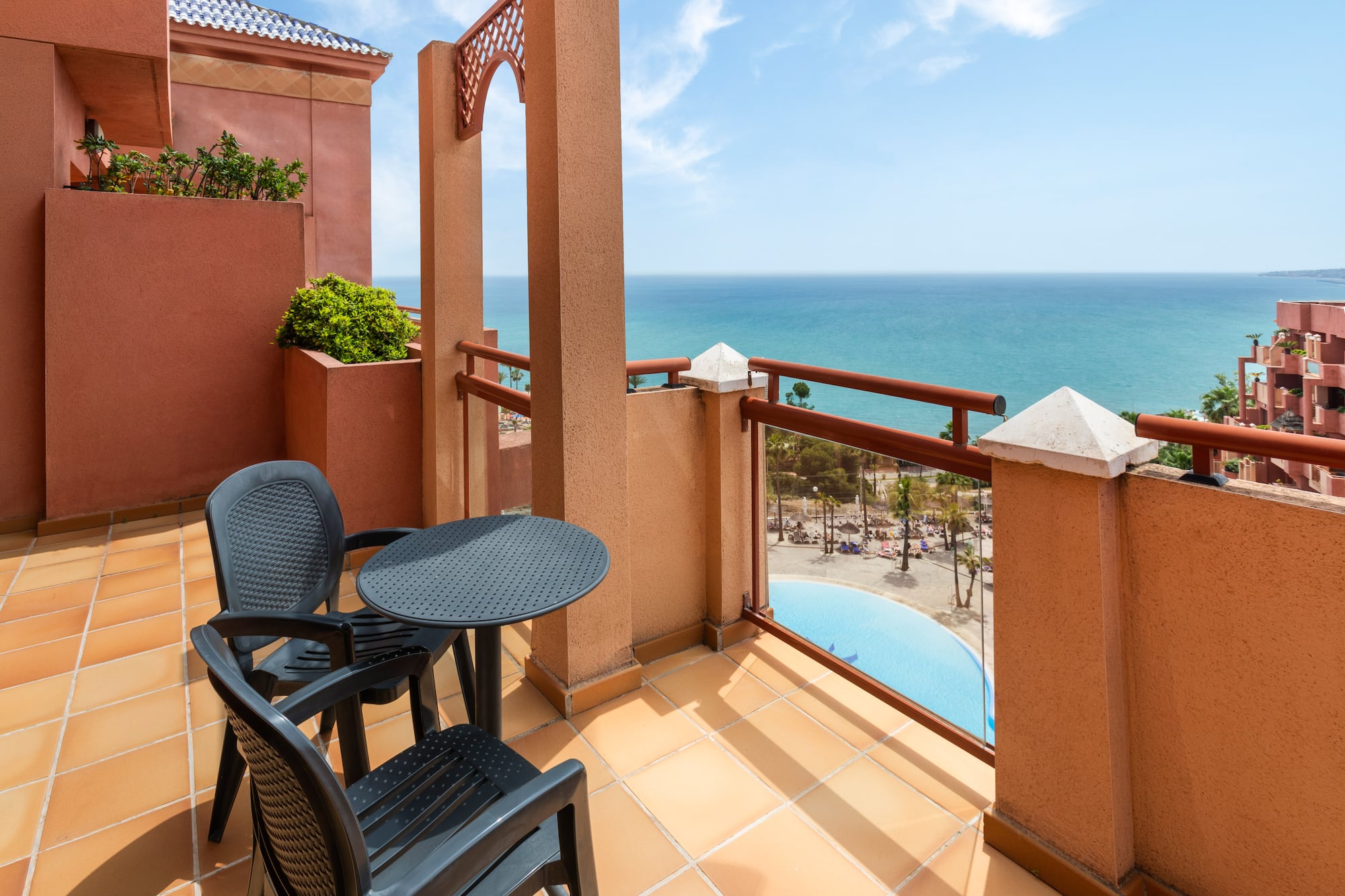 Resort balcony with ocean and pool views, black outdoor furniture.