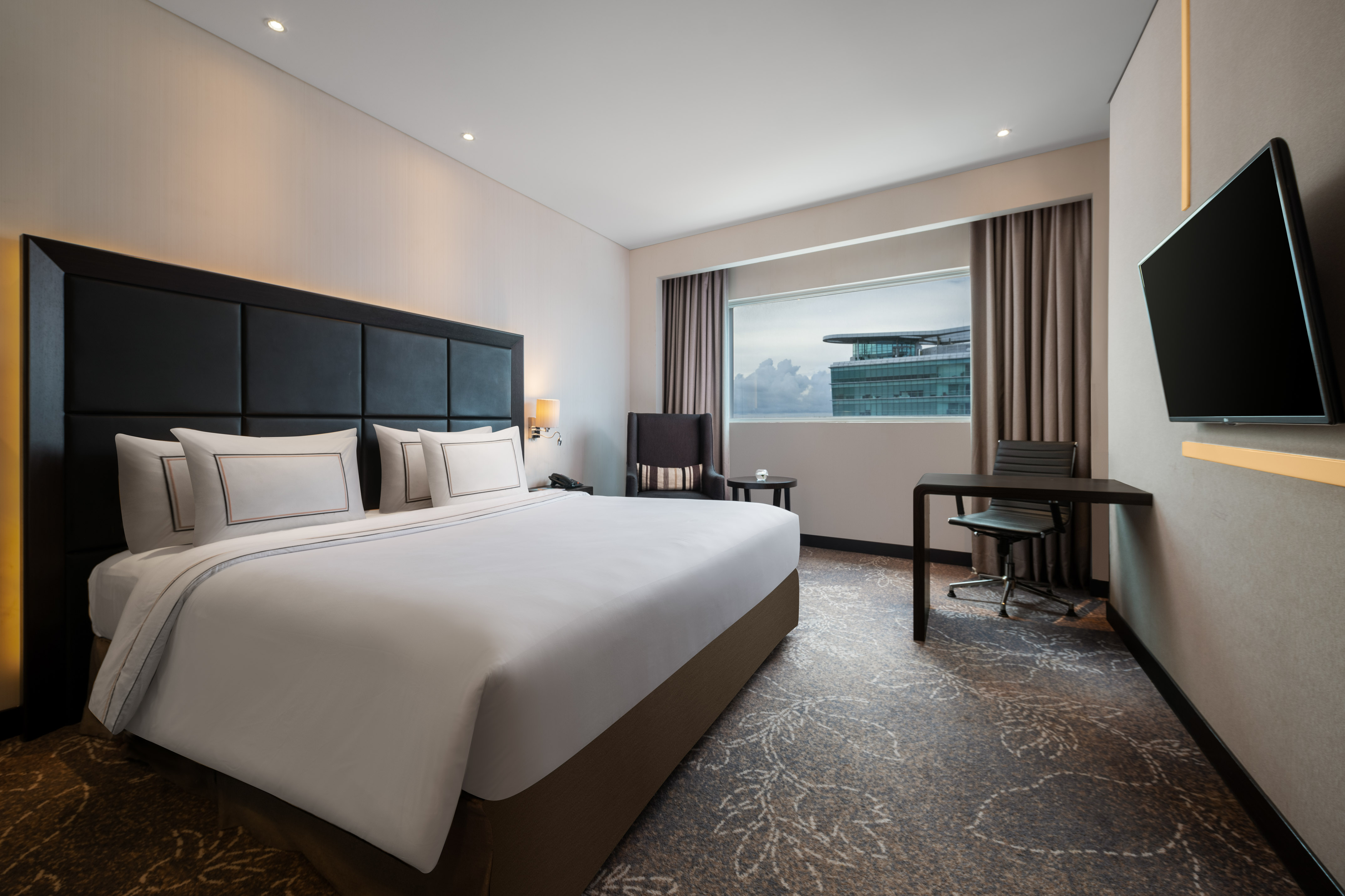 Spacious hotel room featuring a king bed, workstation, TV, and city view.