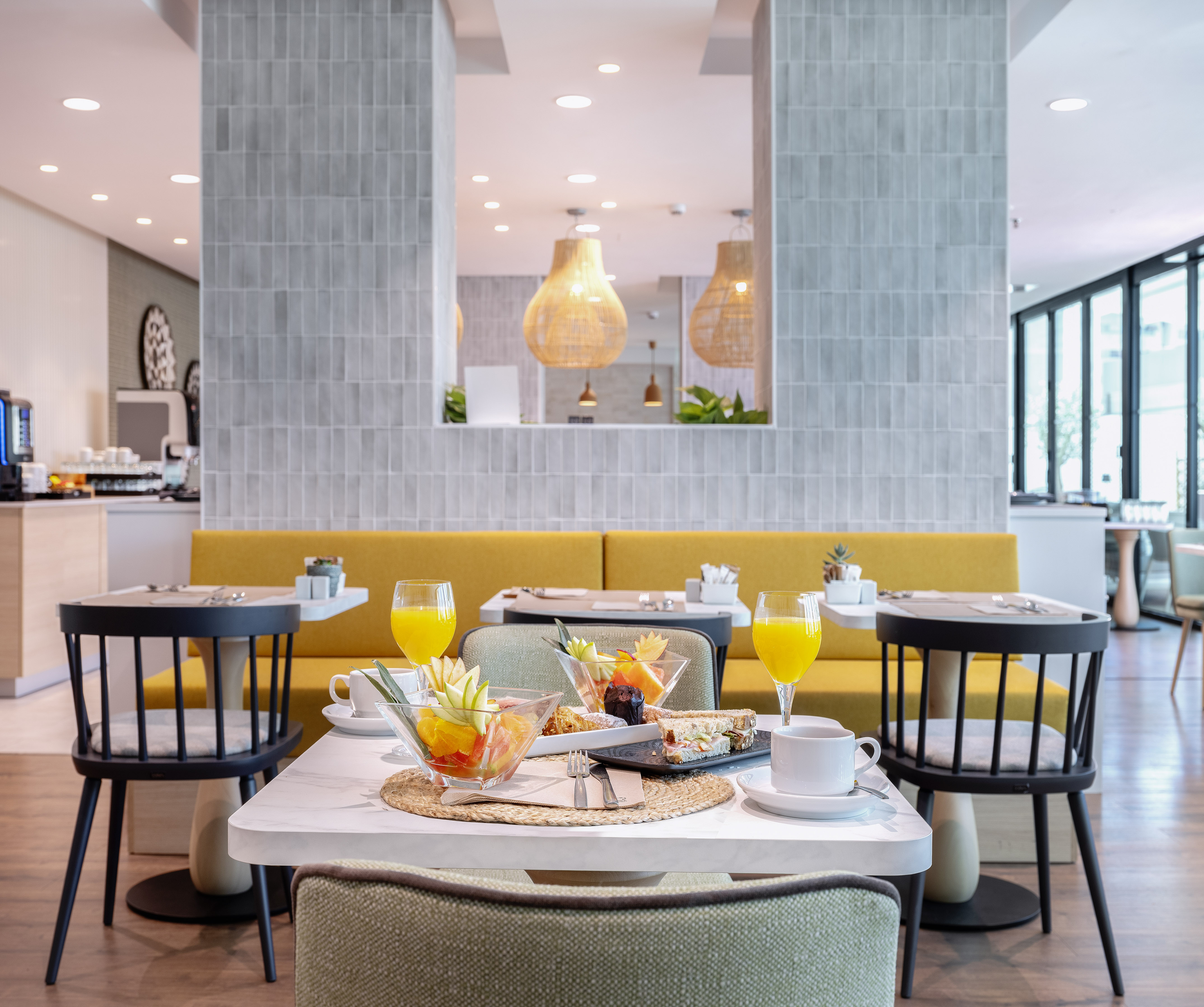 Hotel breakfast table with fresh fruit, sandwiches, orange juice, and coffee.