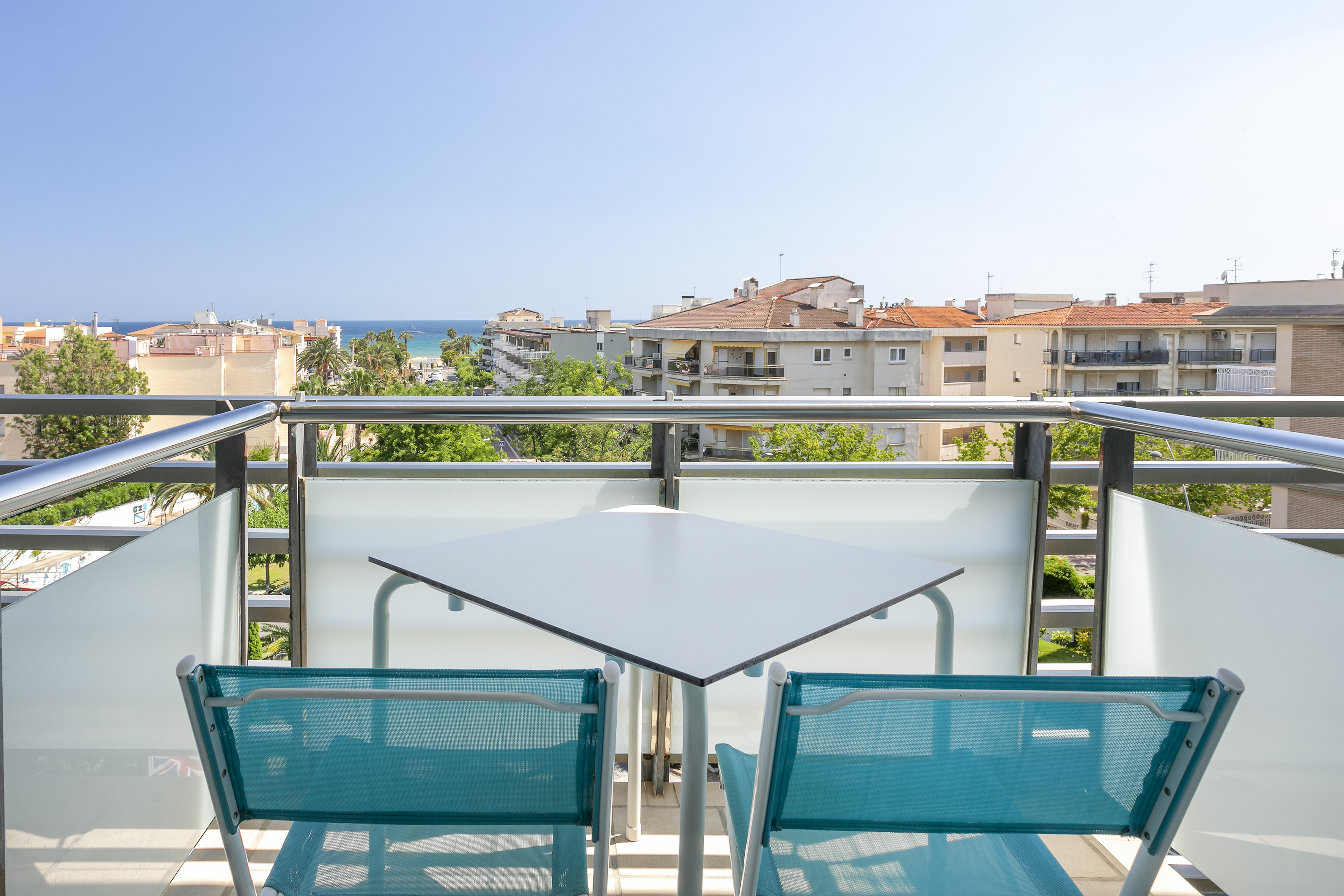 Balcony with table, chairs, coastal city, and ocean view.