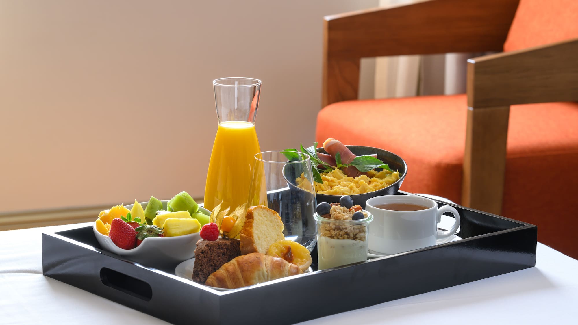 Hotel room service breakfast: fruit, juice, eggs, pastries, yogurt, tea.