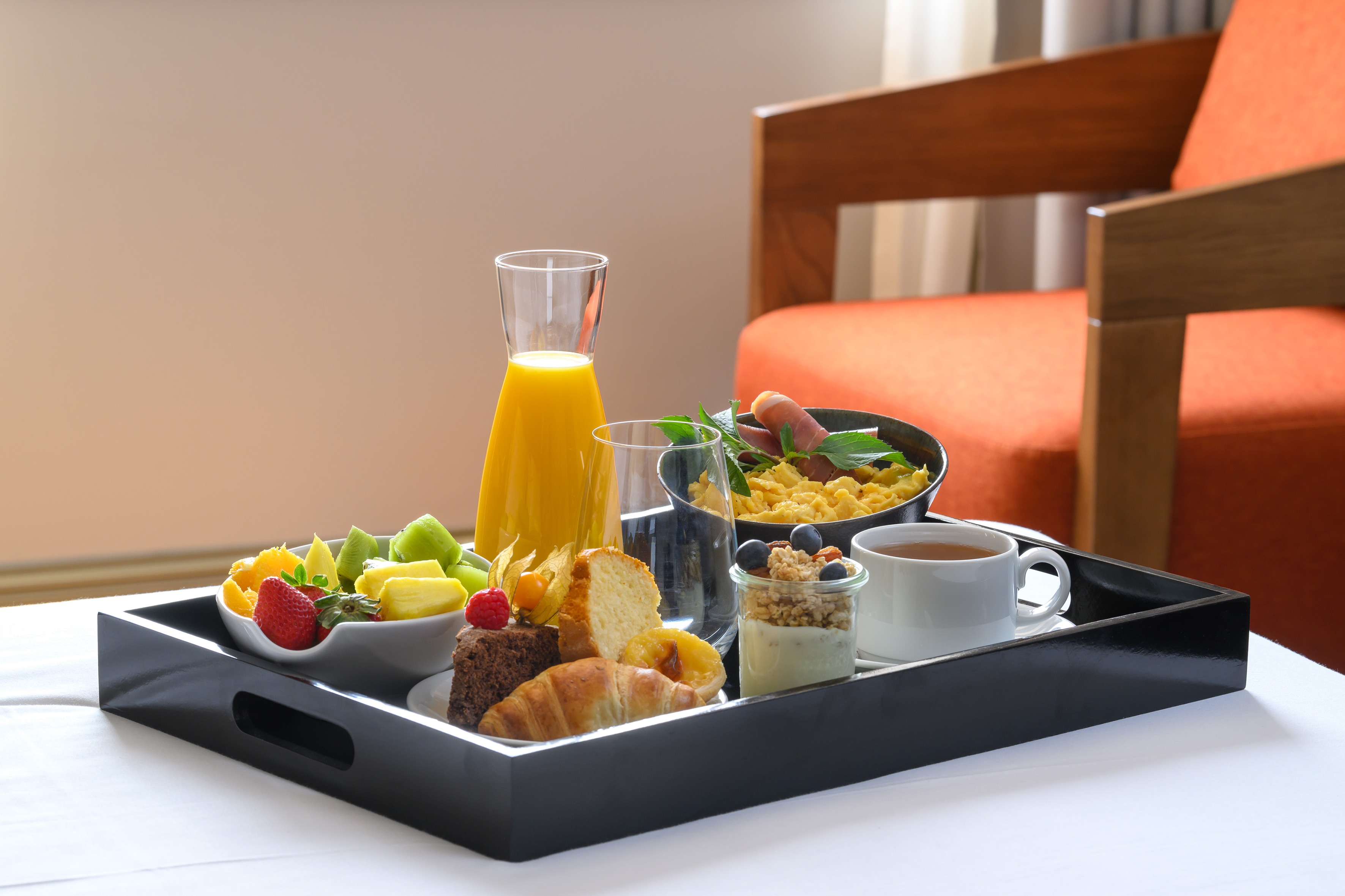 Hotel room service breakfast: fruit, juice, eggs, pastries, yogurt, tea.