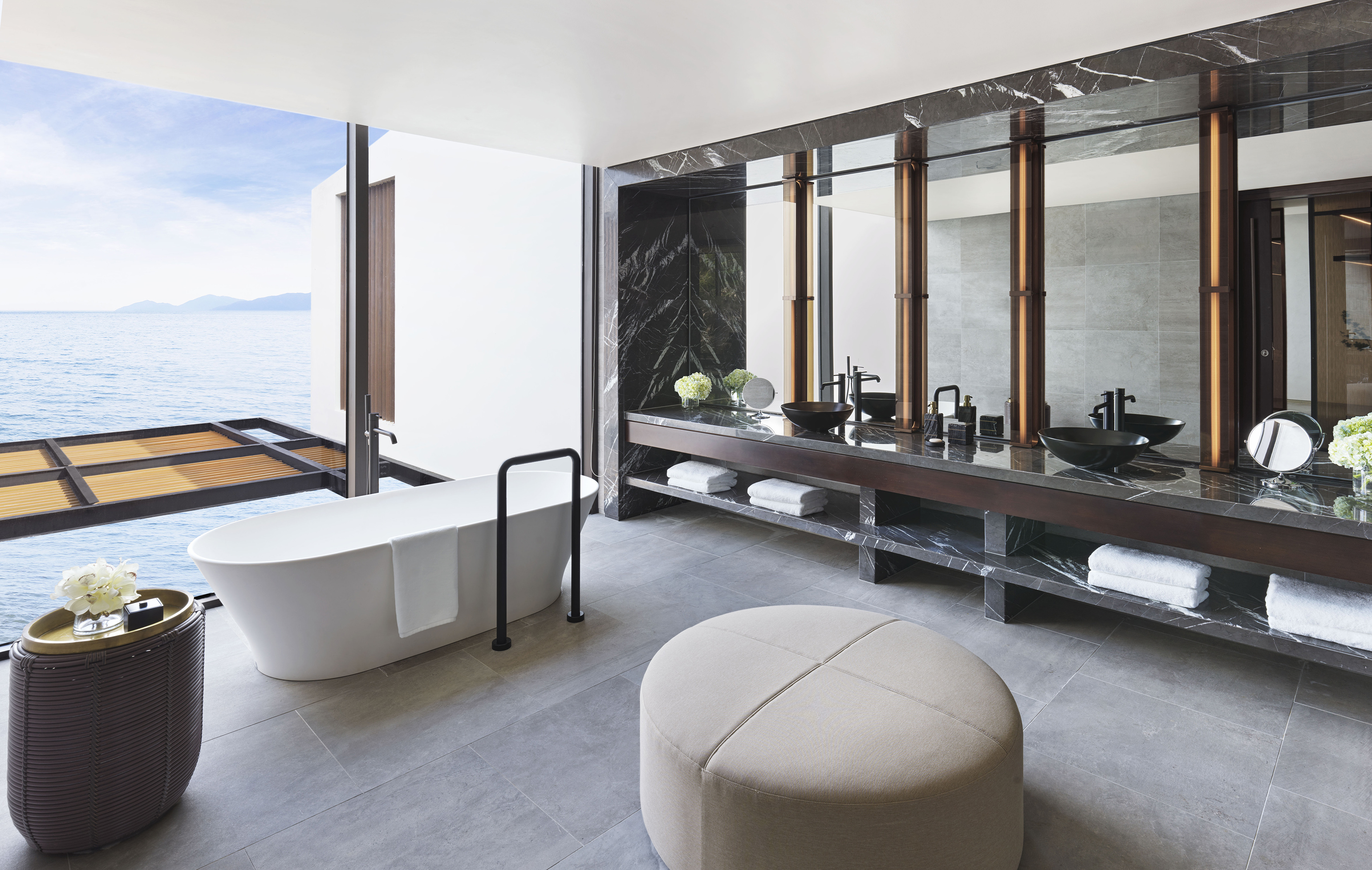 Luxury modern bathroom with ocean view, freestanding tub, and marble vanity.