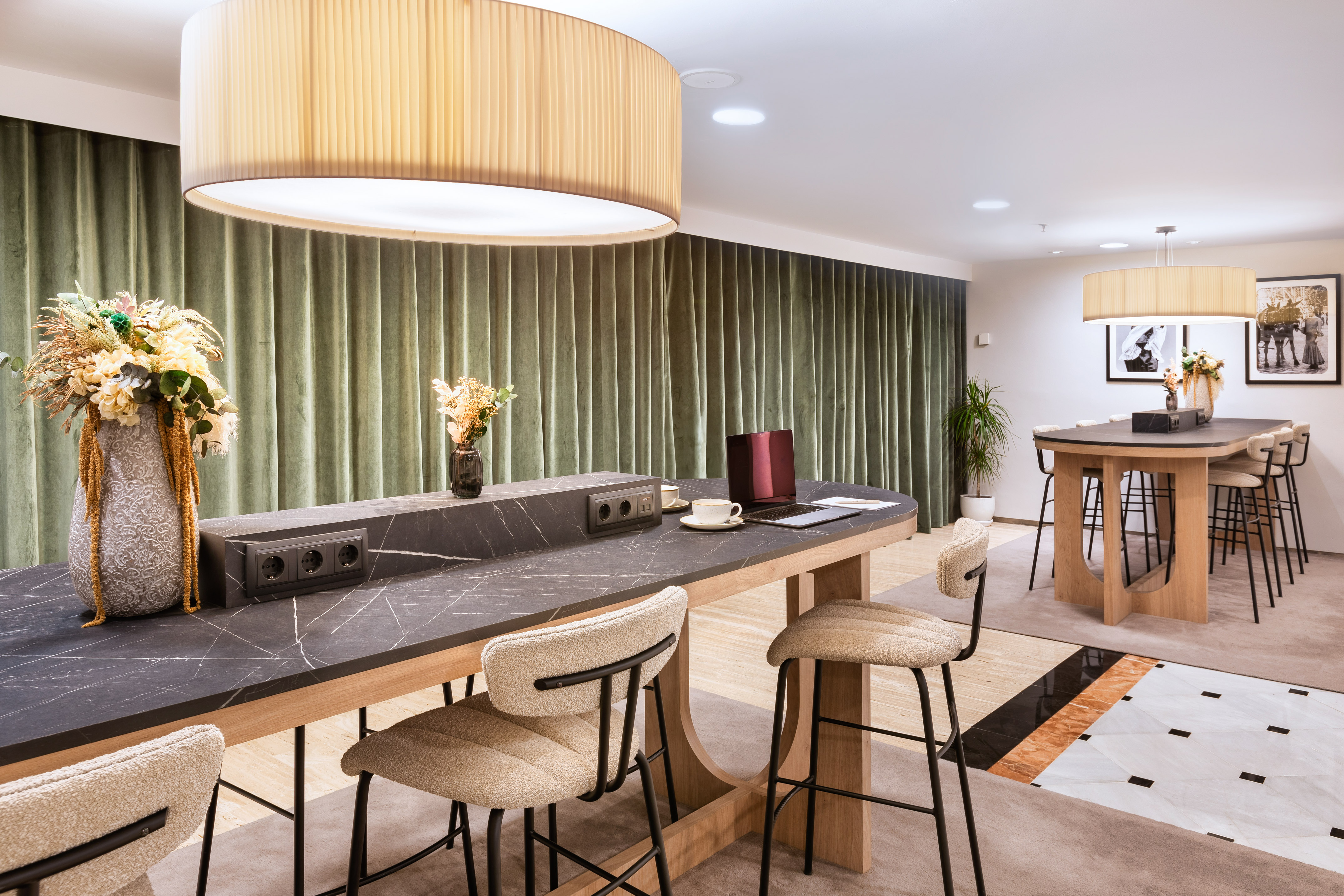 Modern co-working workspace with high tables, bar stools, and green curtains.