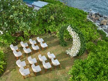 an outdoor wedding setting with white chairs and a arch