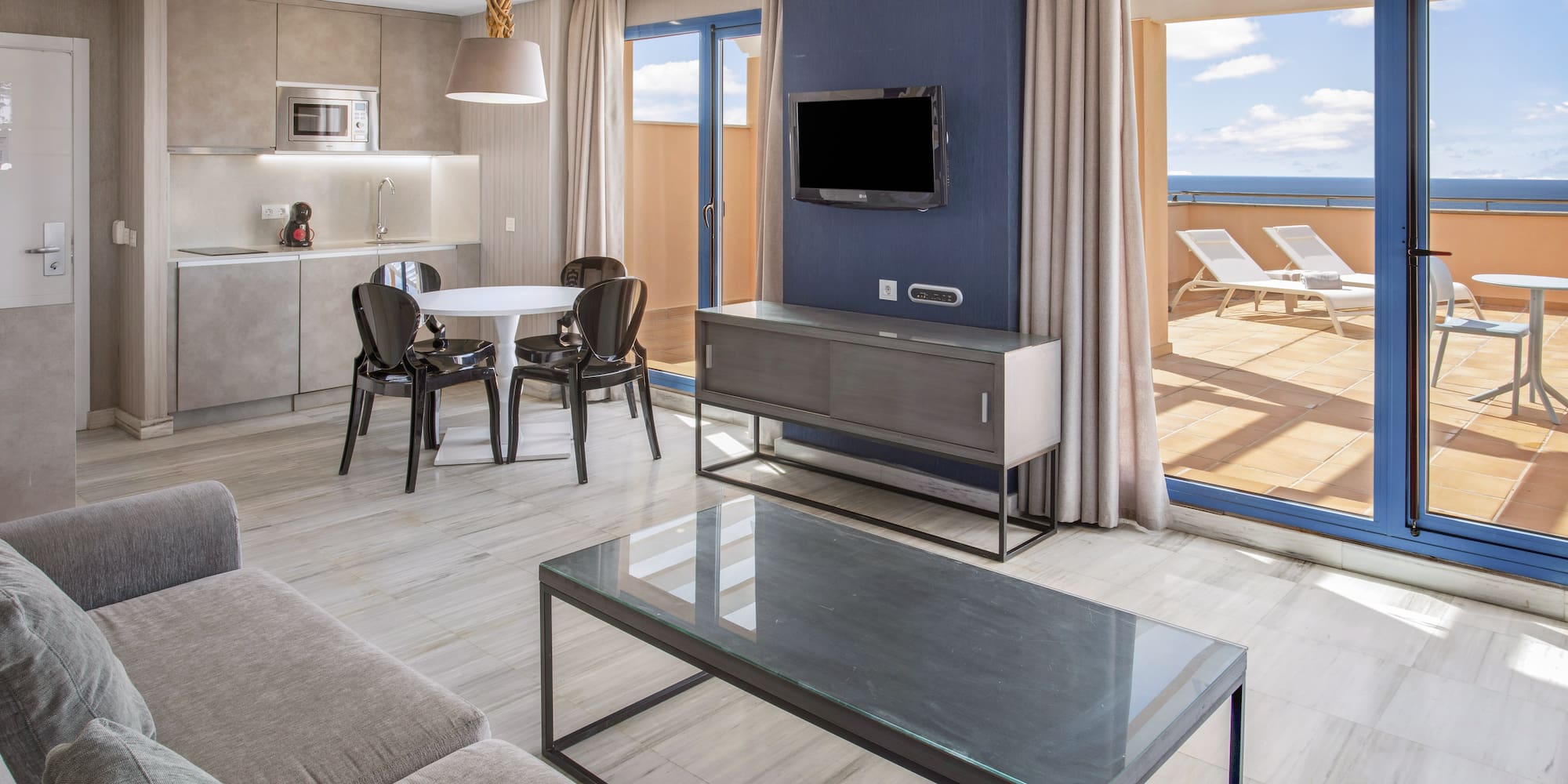 Modern apartment living room, kitchen, dining, ocean view terrace.