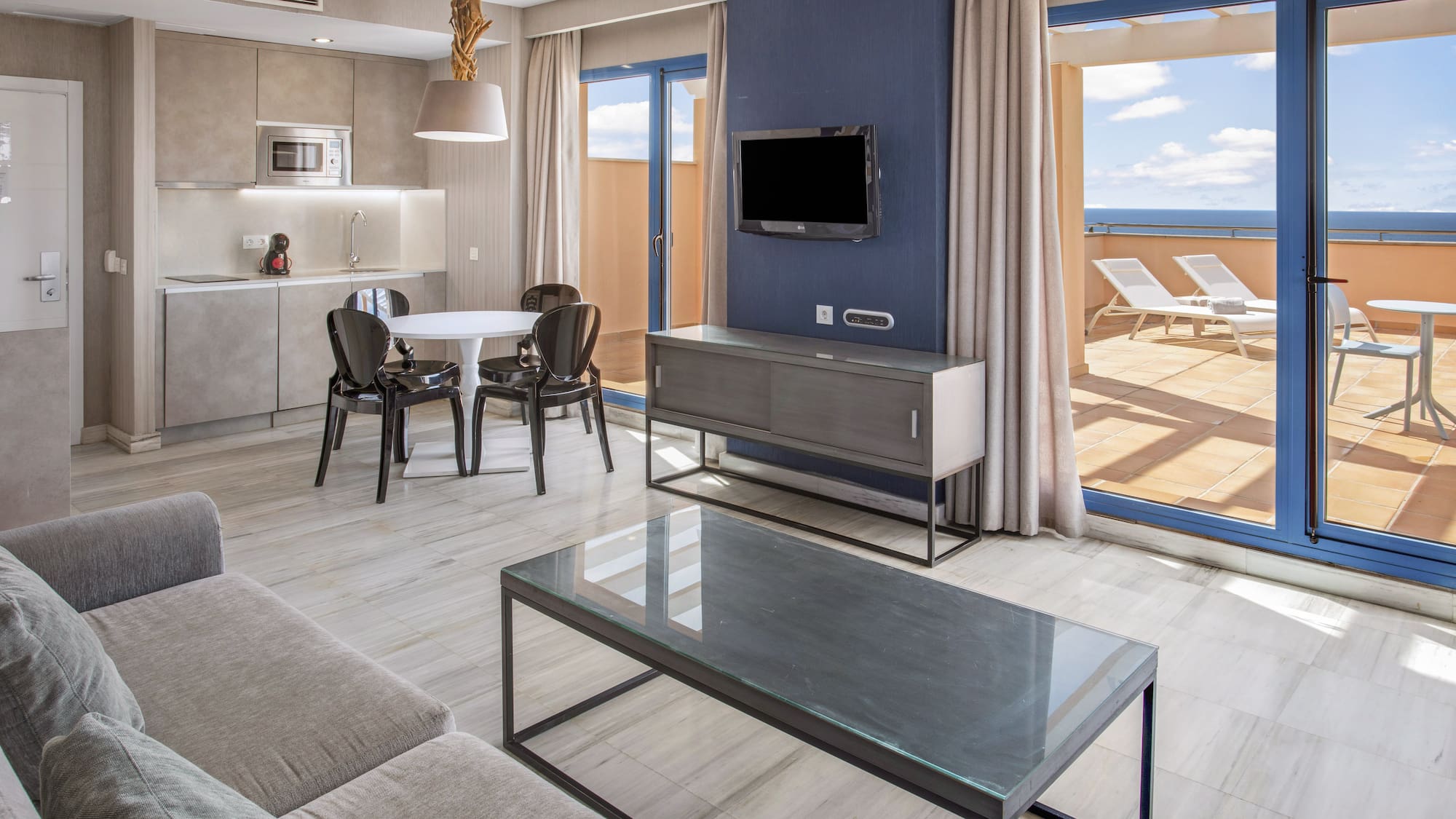 Modern apartment living room, kitchen, dining, ocean view terrace.