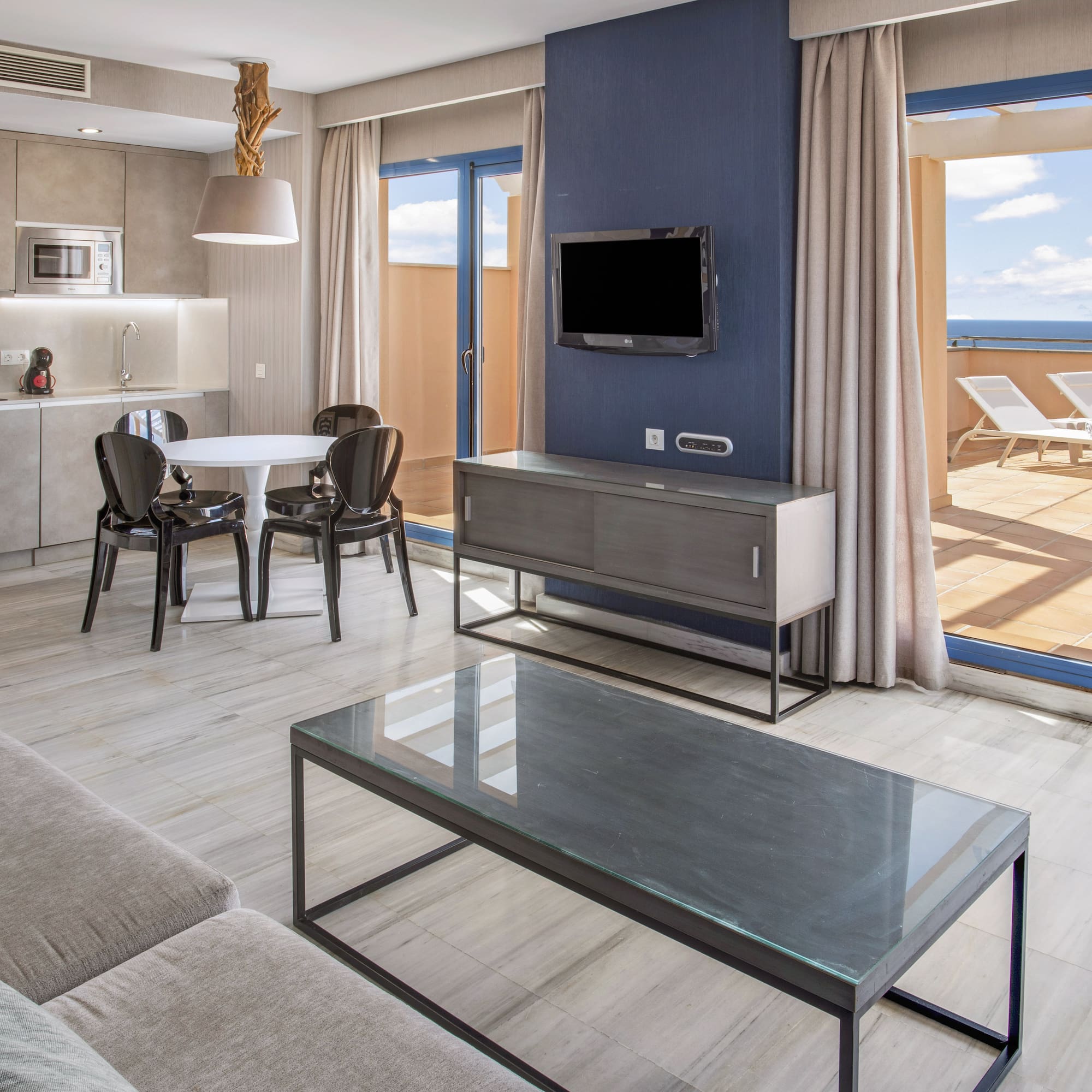 Modern apartment living room, kitchen, dining, ocean view terrace.