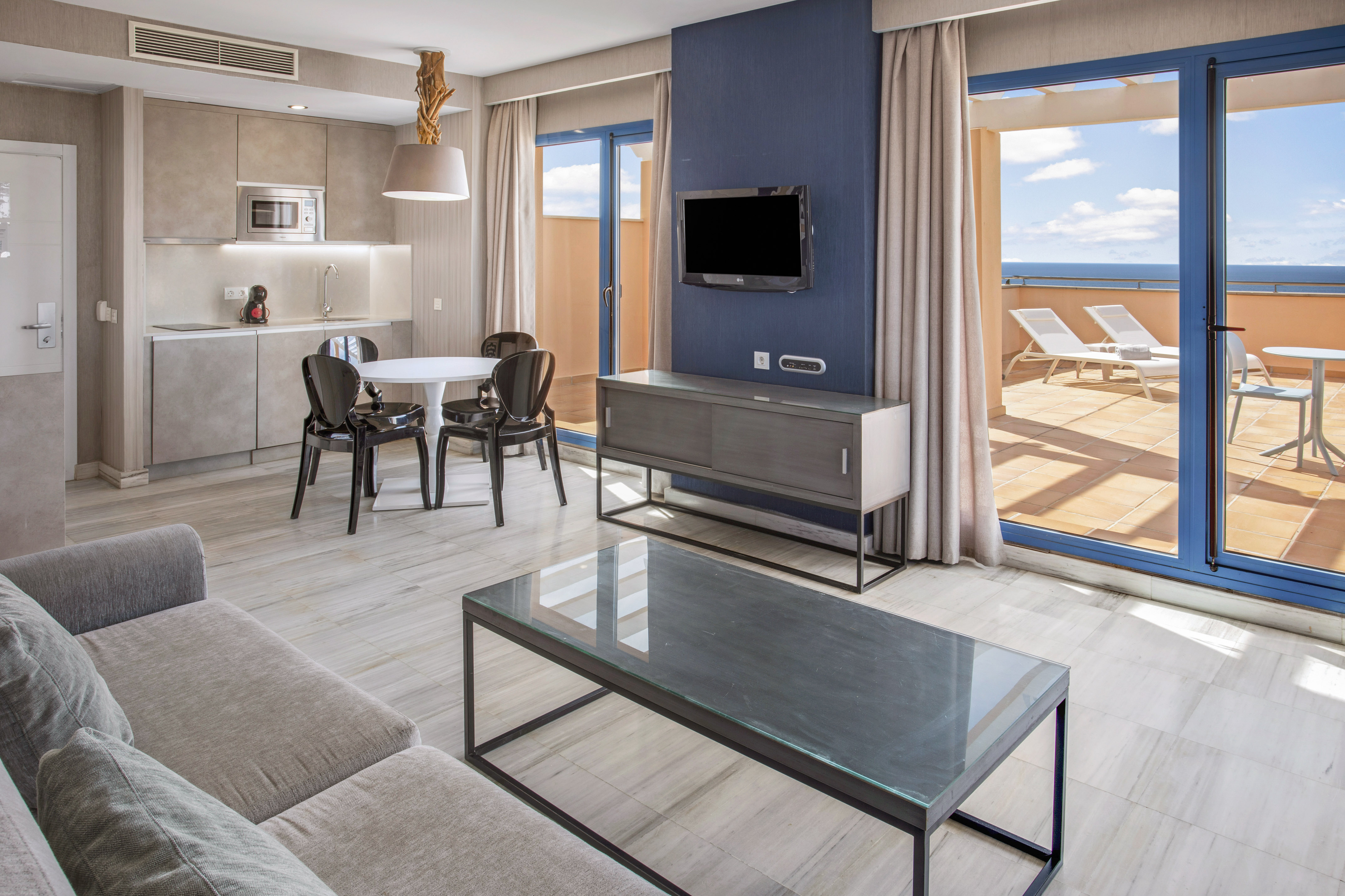 Modern apartment living room, kitchen, dining, ocean view terrace.