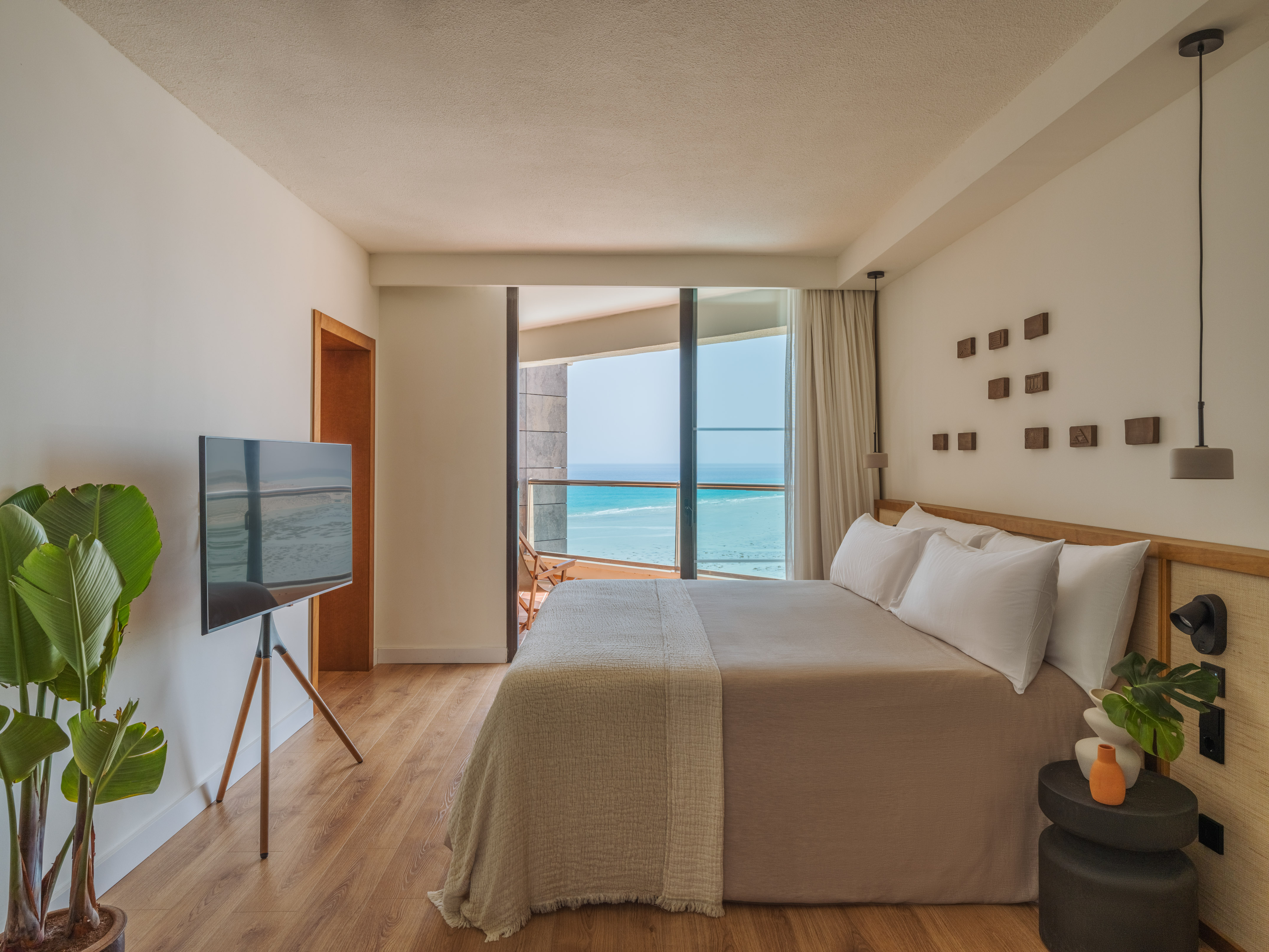 Modern hotel room with ocean view, large bed, and balcony.