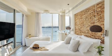 a bedroom with a bathtub and a large window overlooking the water