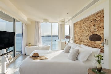 a bedroom with a bathtub and a large window overlooking the water