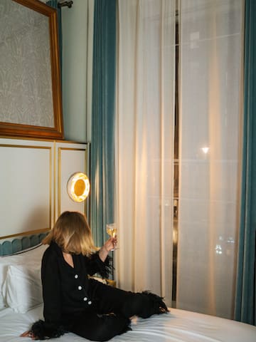 a woman sitting on a bed holding a glass of wine