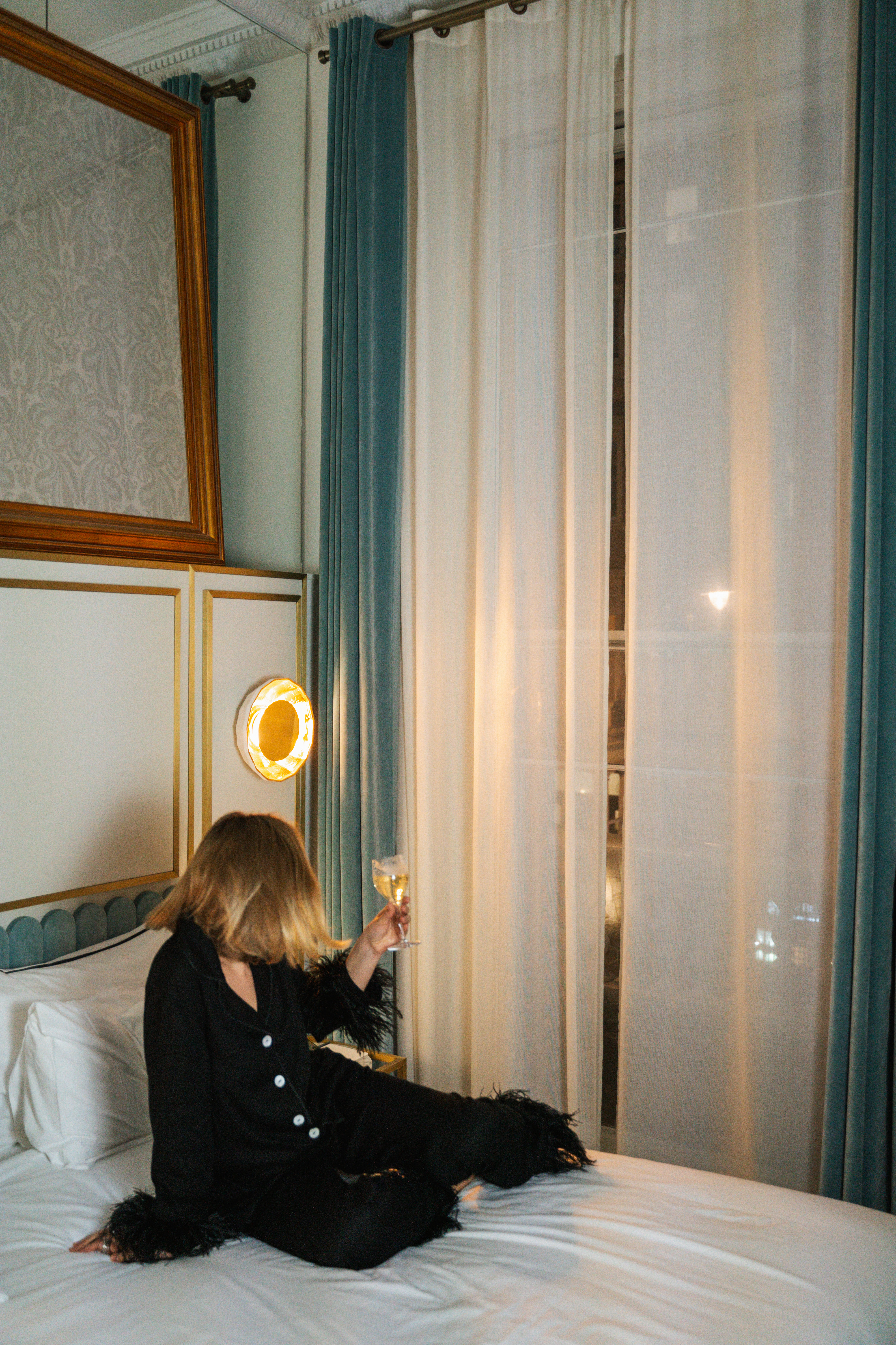 a woman sitting on a bed holding a glass of wine