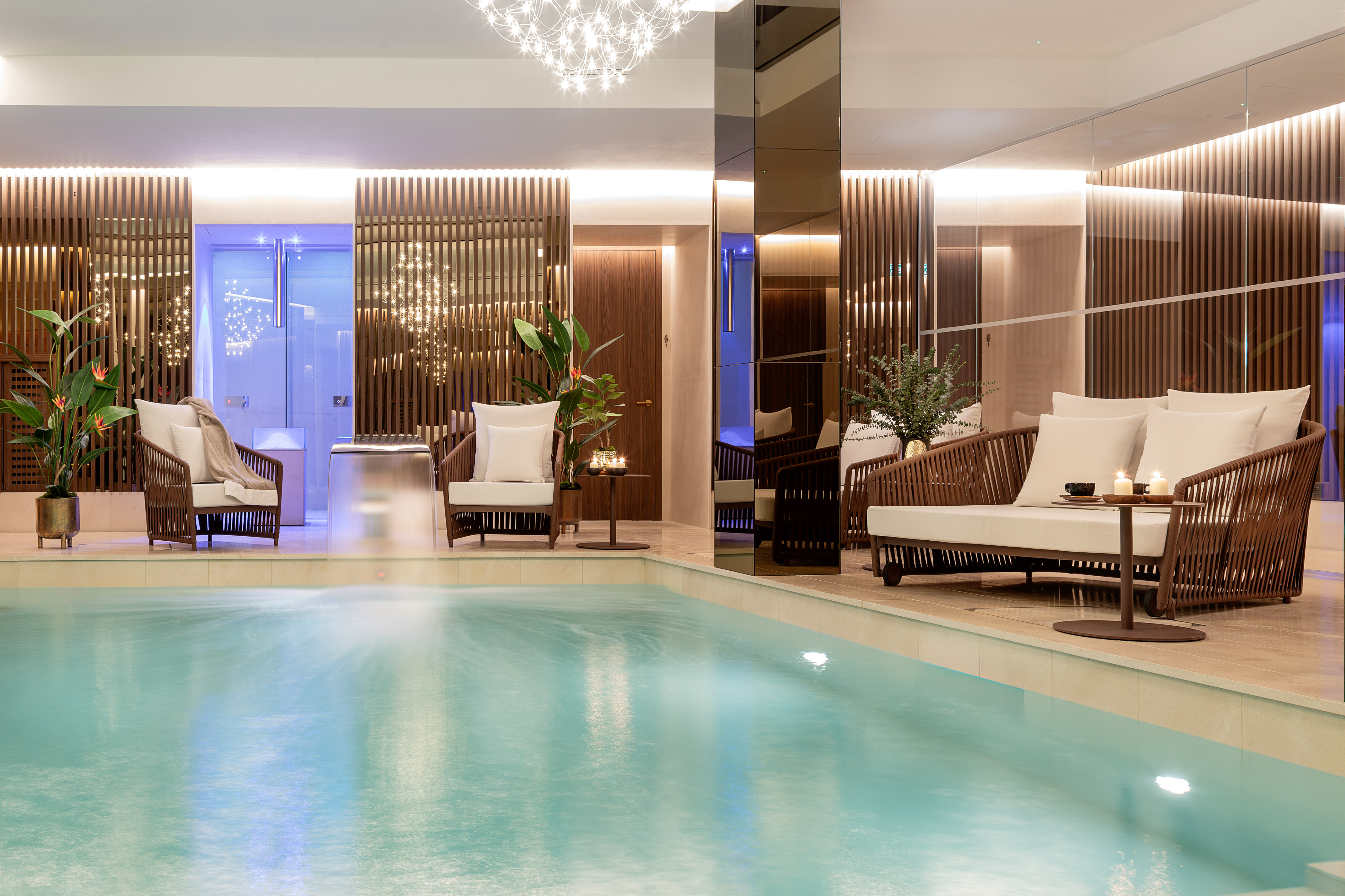 Luxury indoor spa pool with modern lounge area and ambient lighting.