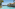 Infinity pool overlooking ocean, with palm trees and a tropical resort building.