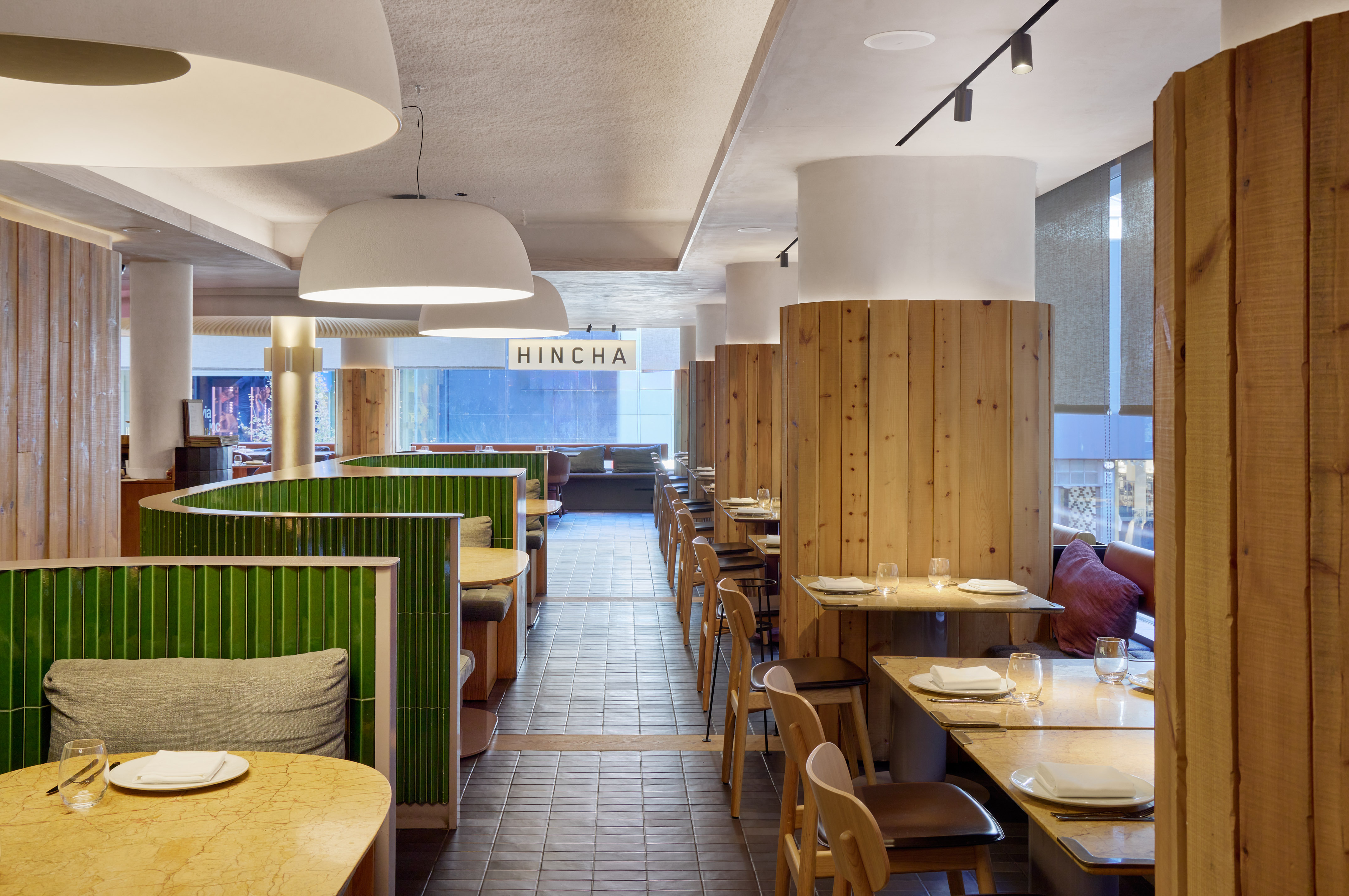 HINCHA restaurant interior with green tiled booths and natural wood paneling.