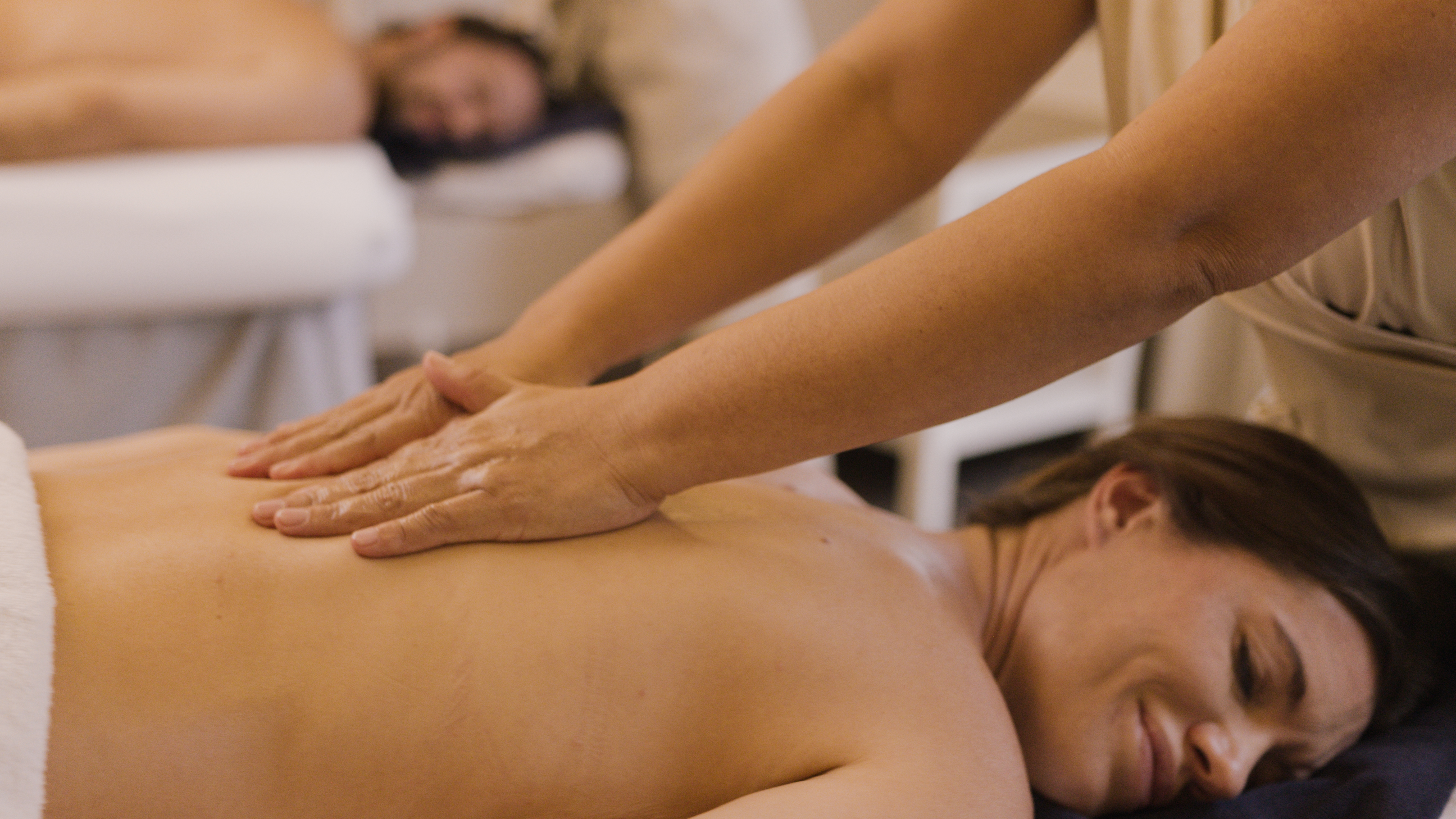 Woman enjoying a relaxing back massage, possibly a couples spa treatment.