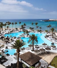 a swimming pool with palm trees and a beach