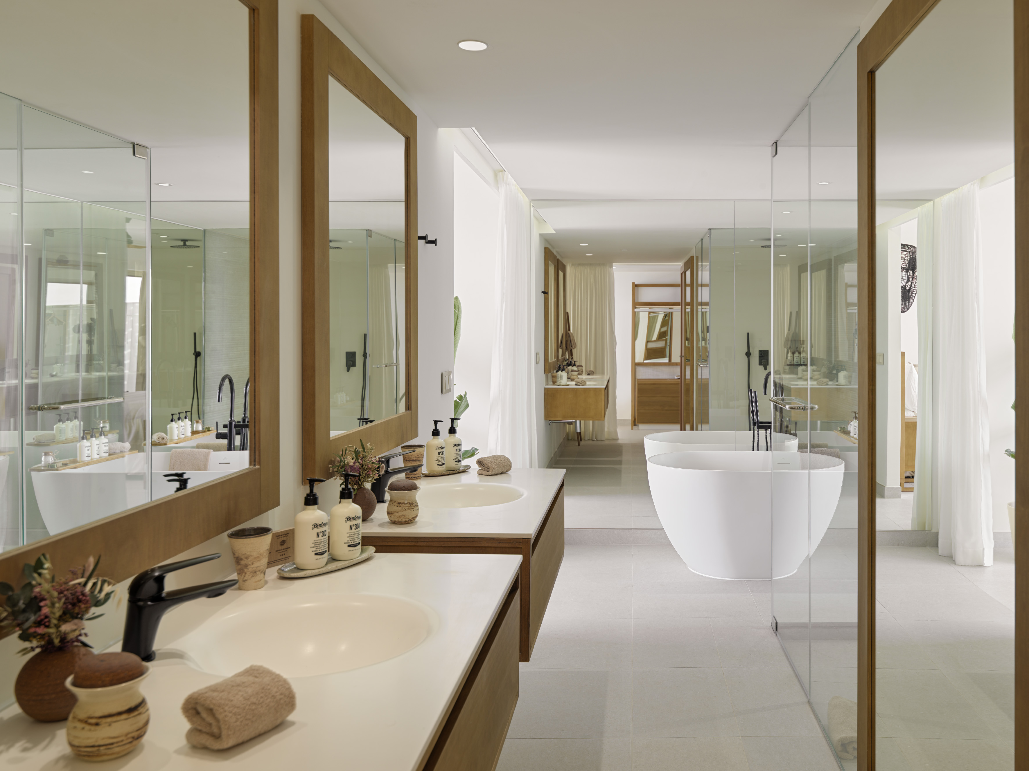 Modern spa bathroom with double vanity, freestanding tub, and glass shower.